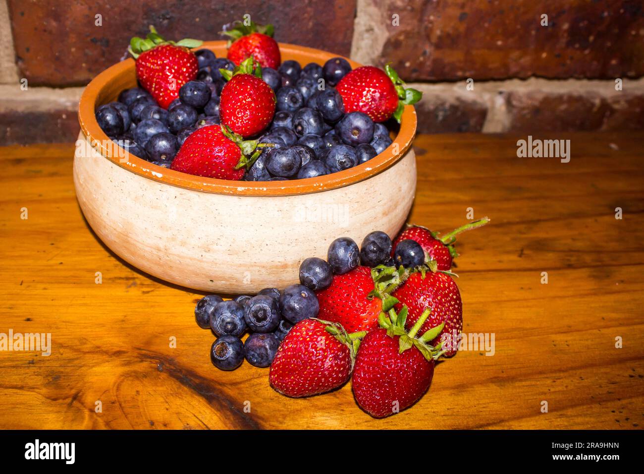 Rustic view of a bowl filled with sweet Strawberries and Blueberries Stock Photo