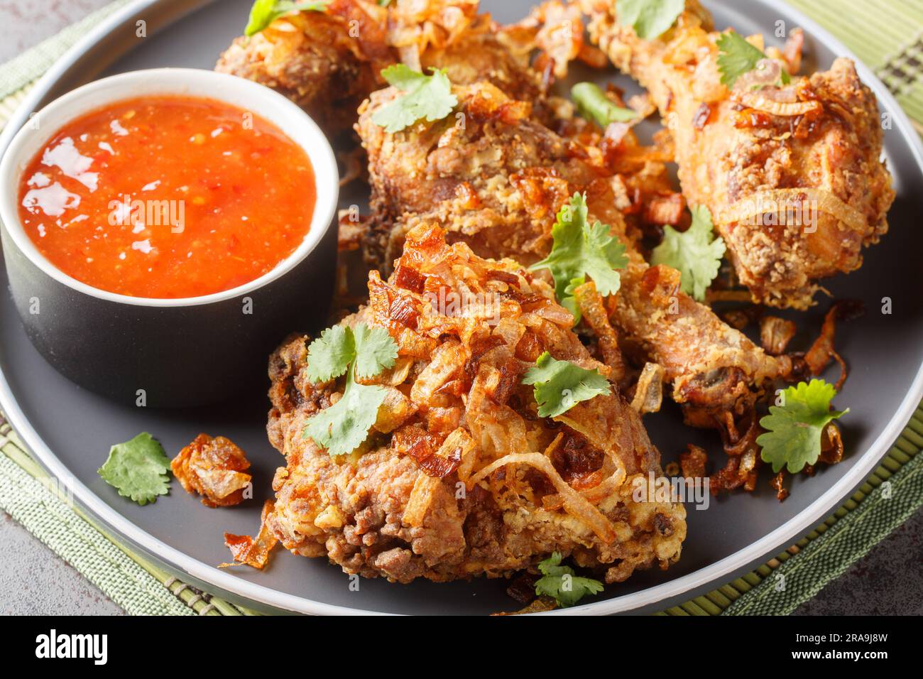 Crisp and Juicy Thai Fried Chicken marinated with cilantro, garlic and Asian seasonings close-up on a plate on the table. Horizontal Stock Photo