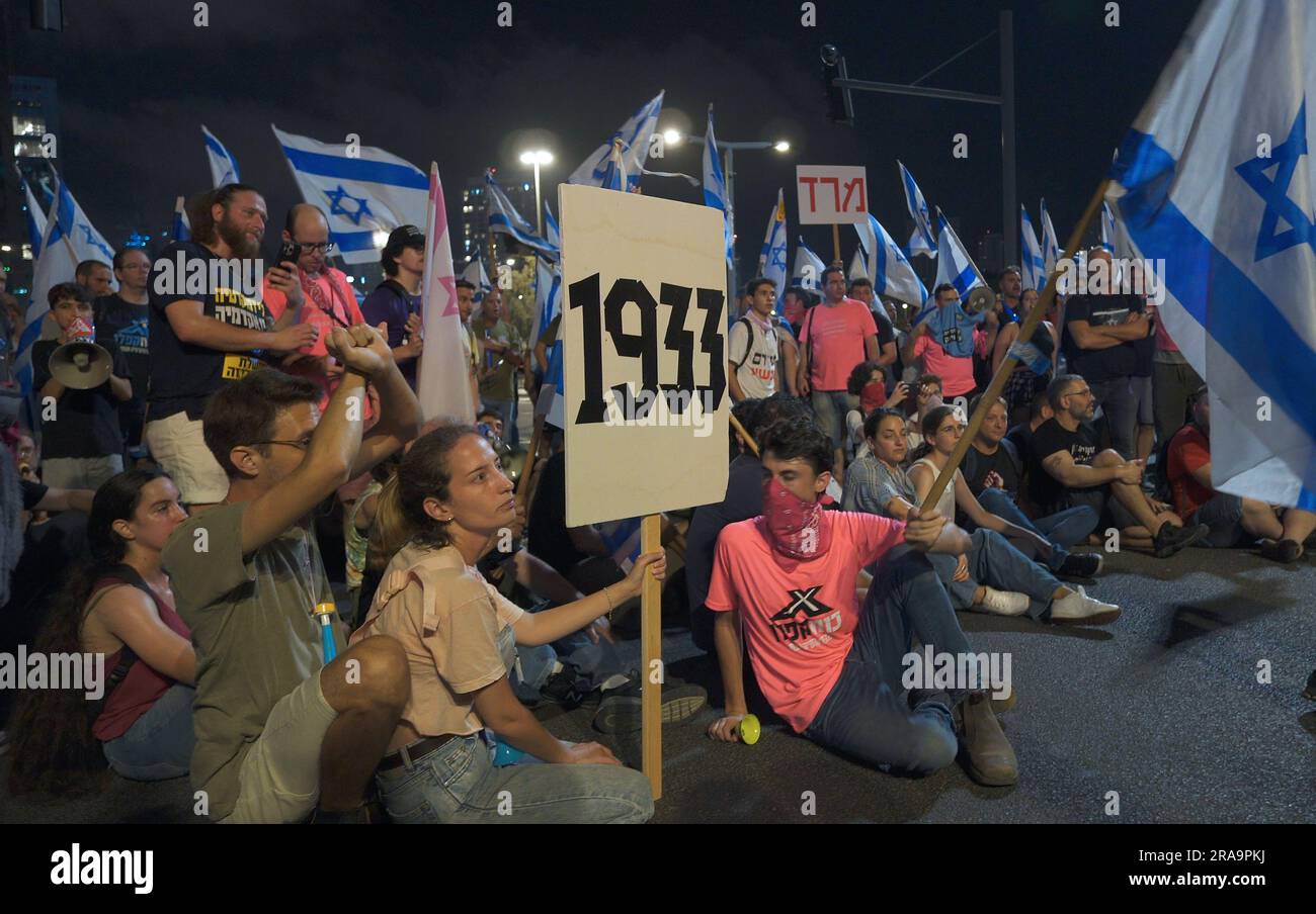 TEL AVIV, ISRAEL - JULY 1: Anti-government protestors hold a sign with the number 1933; which is the year Hitler came to power, as they block a major highway during a demonstration for the 26th consecutive week against PM Benjamin Netanyahu and Israel's hard-right government judicial system plan that aims to weaken the country's Supreme Court on July 1, 2023 in Tel Aviv, Israel. Protests against Israel's right-wing coalition and its proposed judicial changes have been taking place since 7 January. Credit: Eddie Gerald/Alamy Live News Stock Photo