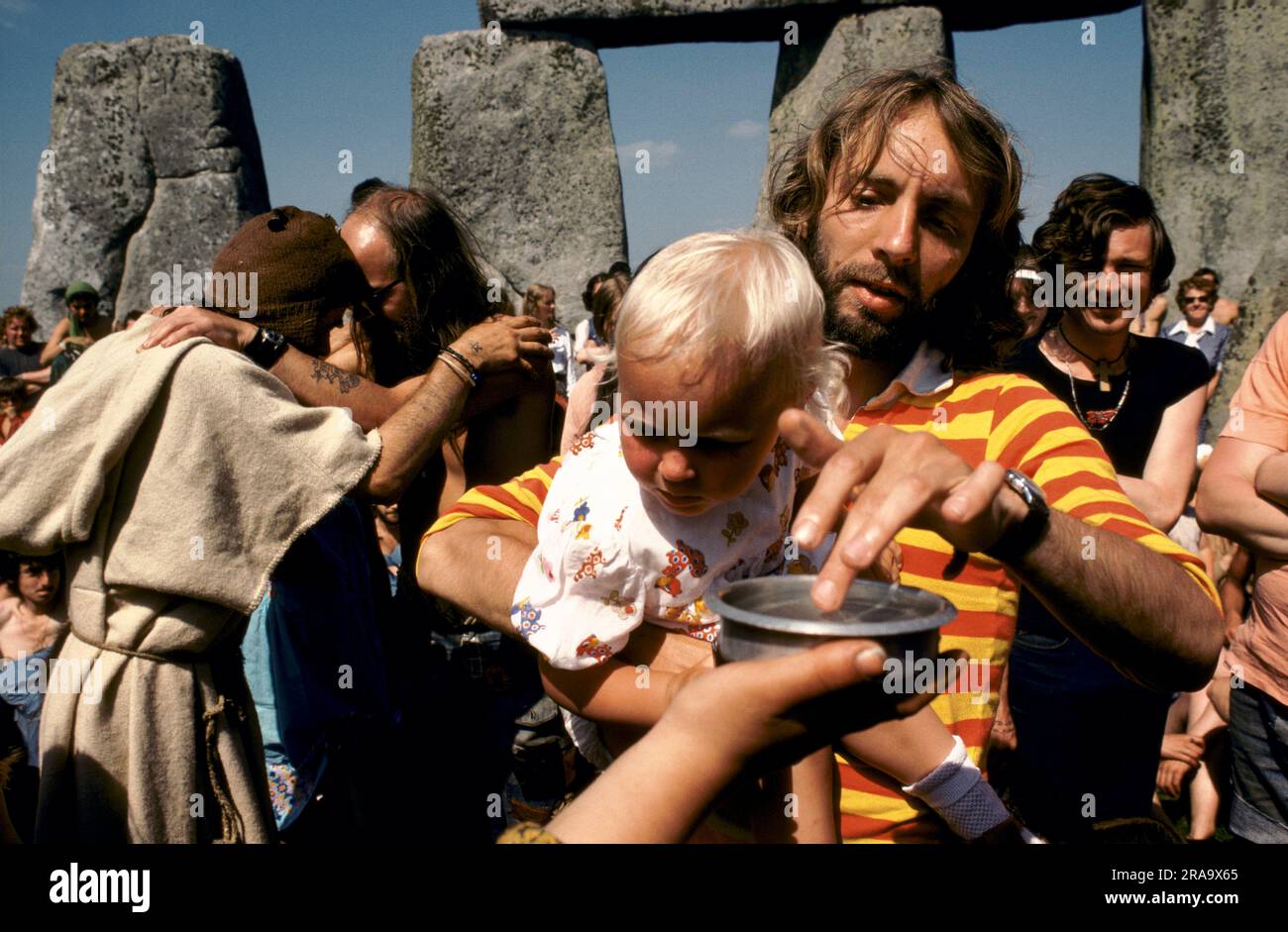 Children are baptised with blessed water. Stonehenge Free Festival at the summer solstice, 1970s style hippies attend the free festival at Stonehenge to celebrate the summer solstice. Wiltshire, England June 21st 1979 70s UK HOMER SYKES Stock Photo