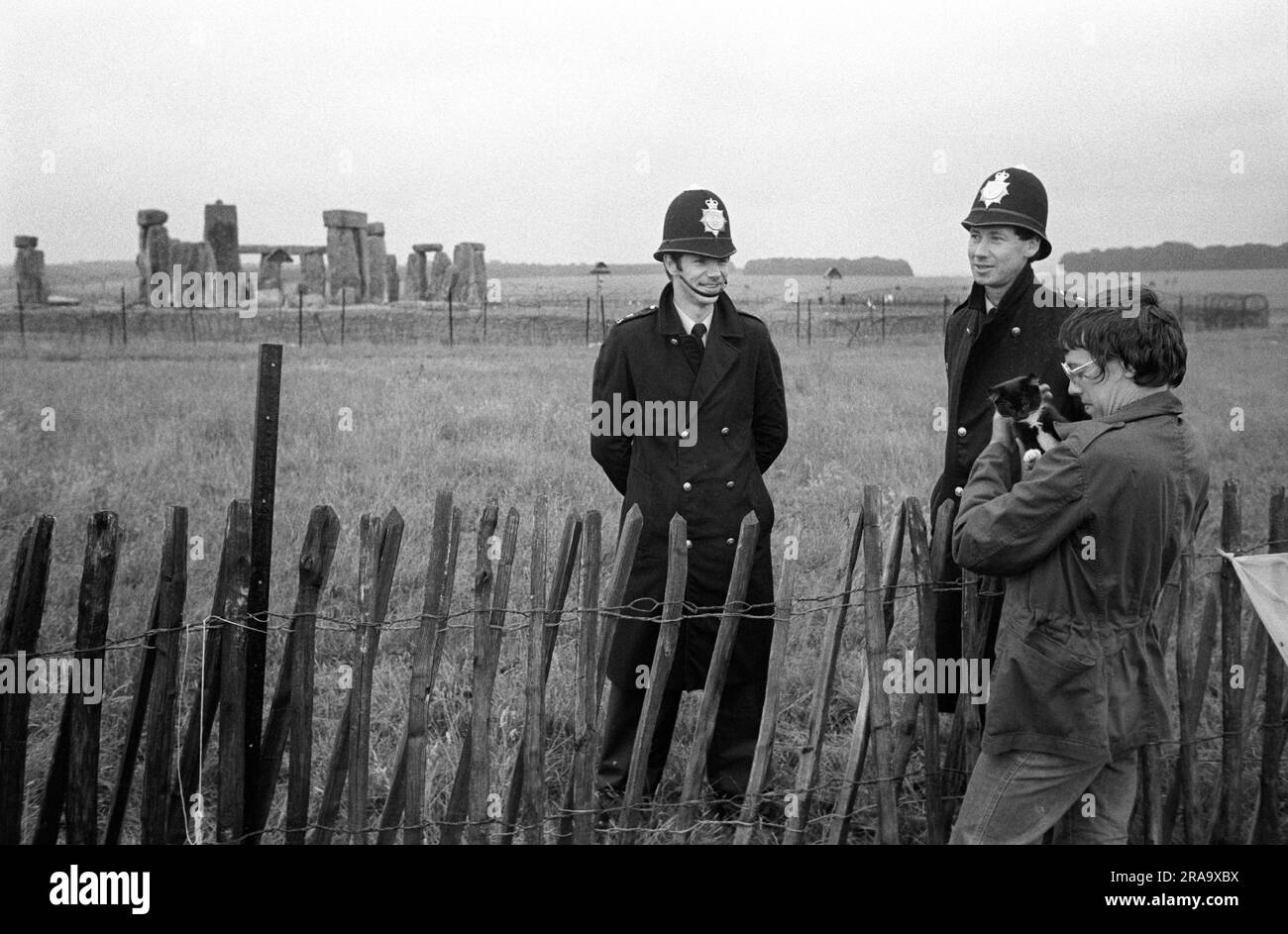 Stonehenge Free Festival at the summer solstice, Wiltshire, England circa June 1976. The stone circle out of bounds, two policeman talk to a festival goer who's holding her pet cat. 1970s UK HOMER SYKES Stock Photo