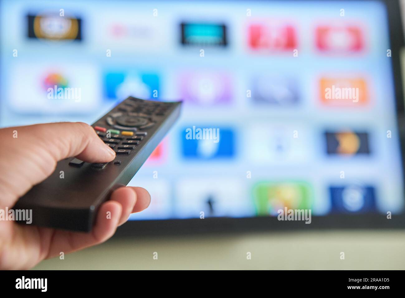 Multimedia streaming concept. Hand holding remote control. TV screen
