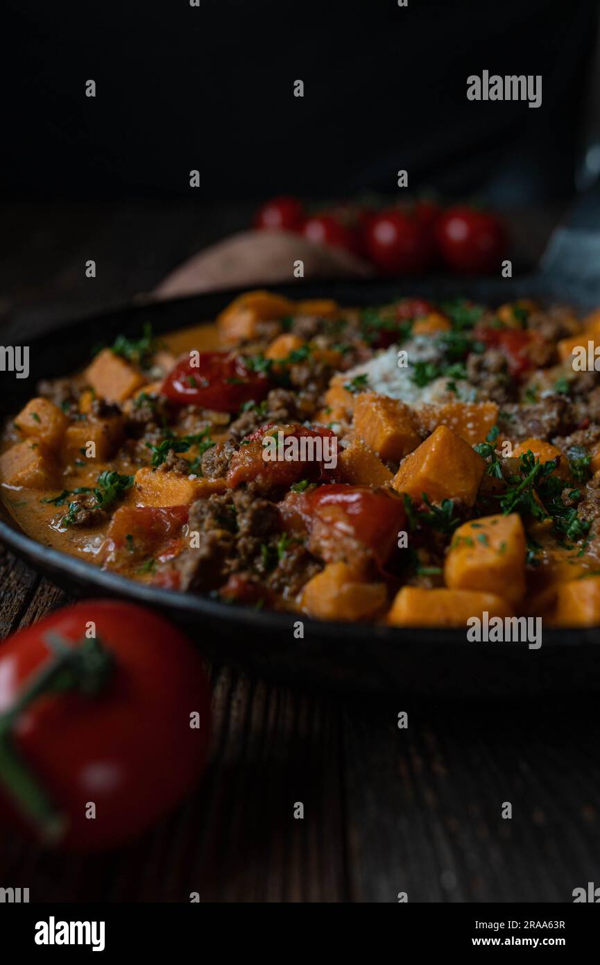 Sweet potato, ground beef with vegetable and parmesan cheese in a cast iron pan Stock Photo