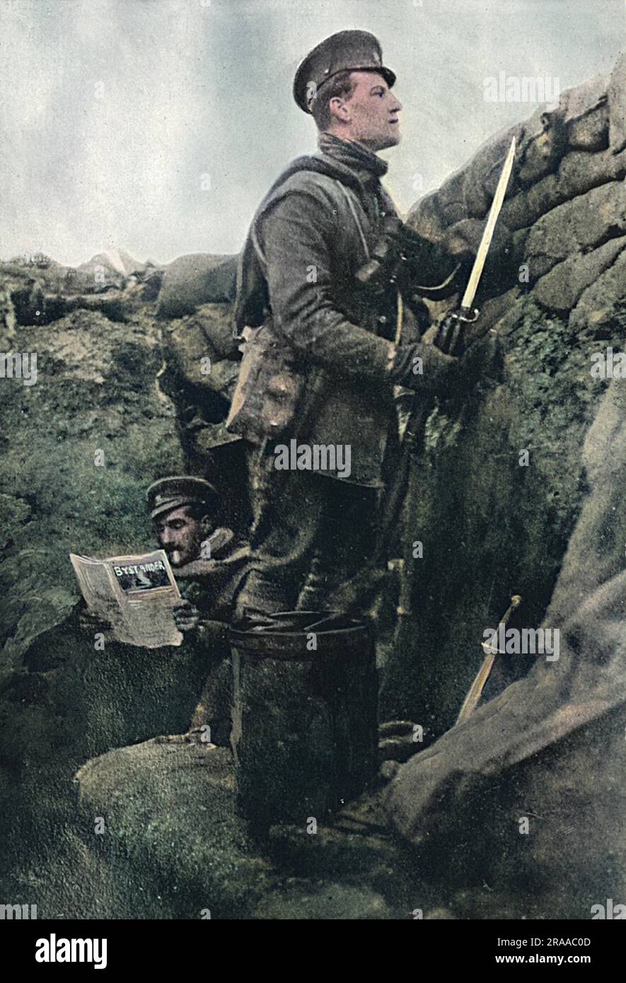 A sentry keeps watch in a British trench while his comrade spends his turn off duty reading a copy of the Bystander, 'the latest issue of this journal, with its reminders of the humours of life in the trenches  and joys of life in England now.'  The Bystander, which ran from 1903 to 1940 (when it merged with The Tatler), was a high quality weekly illustrated magazine, first published by The Graphic and later part of the Illustrated Newspapers group.  It cover sport, society, fashion, politics, entertainment and the arts, and published many cartoons and humorous illustrations covering topics of Stock Photo