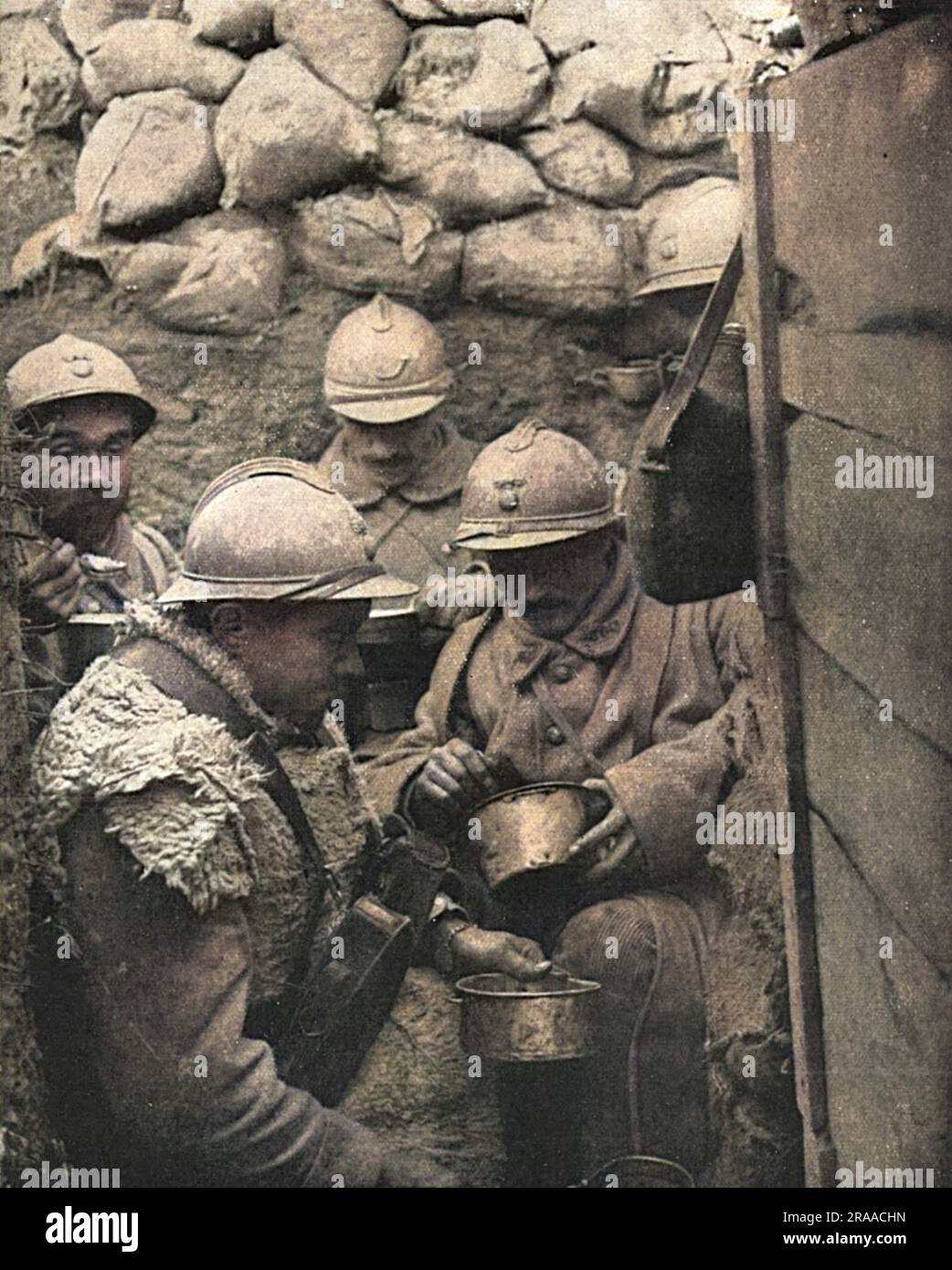 Dinner-time for soldiers in a corner of a fire-trench on the French front in the Argonne. The caption reads: 'The clockwork regularity of the French culinary arrangements at the front, and the food-supply system to the troops in the battlefield region, have been repeatedly remarked on as a wonder of French war organisation'.     Date: 1917 Stock Photo