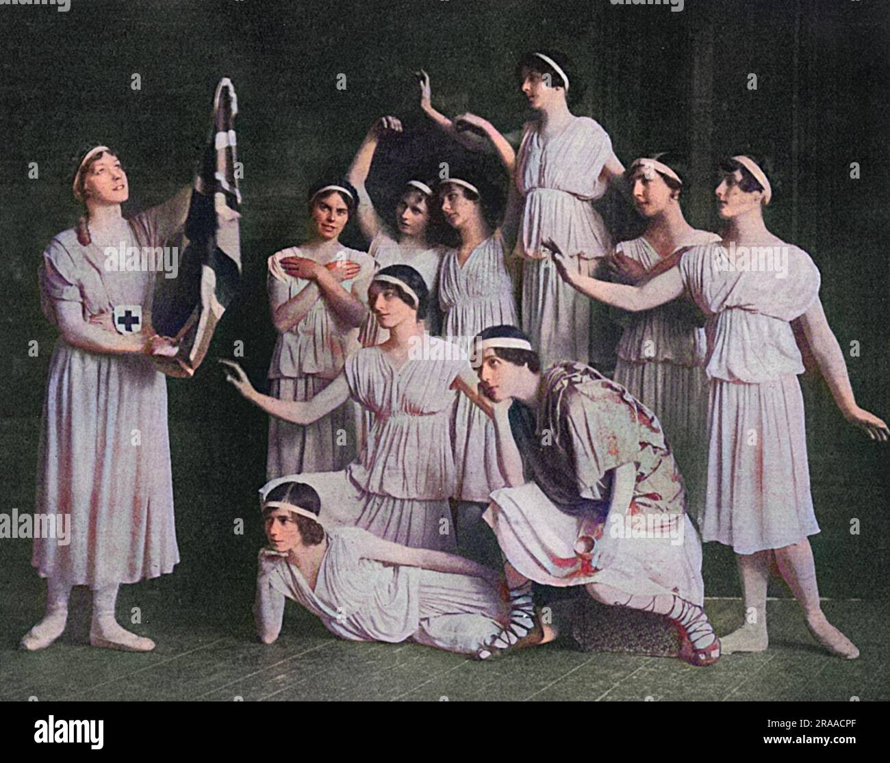 Madame Karina, Danish prima ballerina, pictured with a number of her pupils, all children or sisters of serving officers, taking part in a dance called The Good Angel.  She is seen far left wearing the red cross and carrying a Union Jack flag.  As a fellow Dane, Queen Alexandra was patron of the dancing school.     Date: 1915 Stock Photo