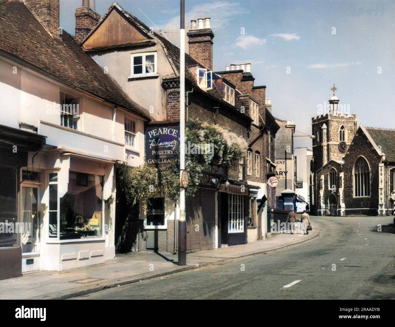 A picturesque corner of Vine Street, Uxbridge, in the London Borough of Hillingdon, England showing a glimpse of a parade of shops and the parish church.     Date: 1950s Stock Photo