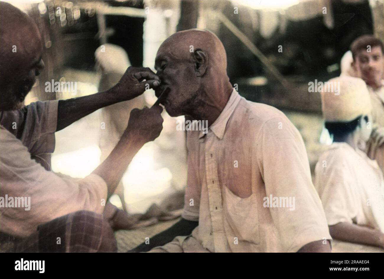A close shave with a cut- throat razor for this man in the United Arab Emirates, who is having his moustache shaved off - ouch!     Date: 1930s Stock Photo
