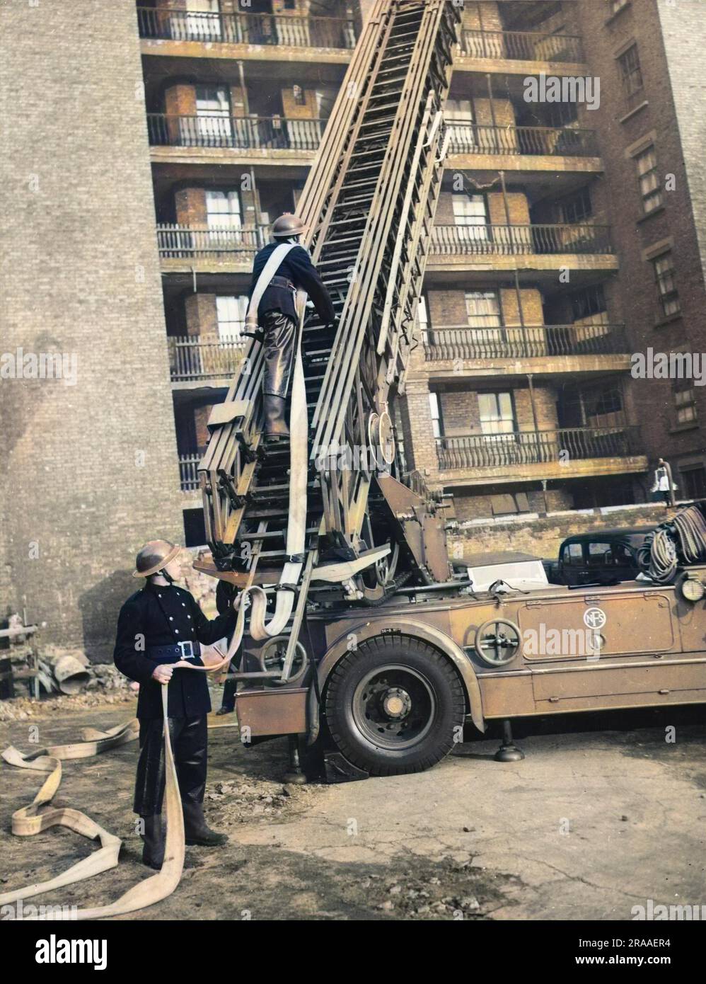 American soldiers on duty with the London Fire Brigade practice British Fire Fighting techniques including climbing up steel turn table ladder. They can then use these skills when they return to civilian life in the United States.     Date: 1939-1945 Stock Photo