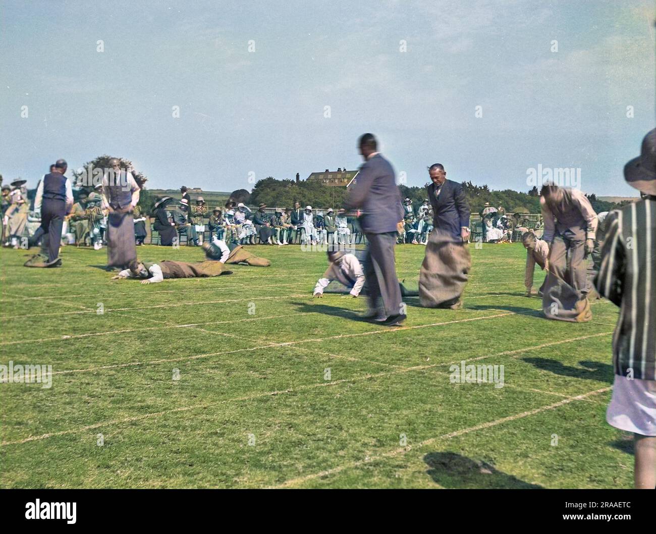 Sporting fathers take part in a sack race designed specially for them at a school sports day in Seaford, Sussex.  Several of them have fallen over, or are in the process of doing so.     Date: 1934 Stock Photo