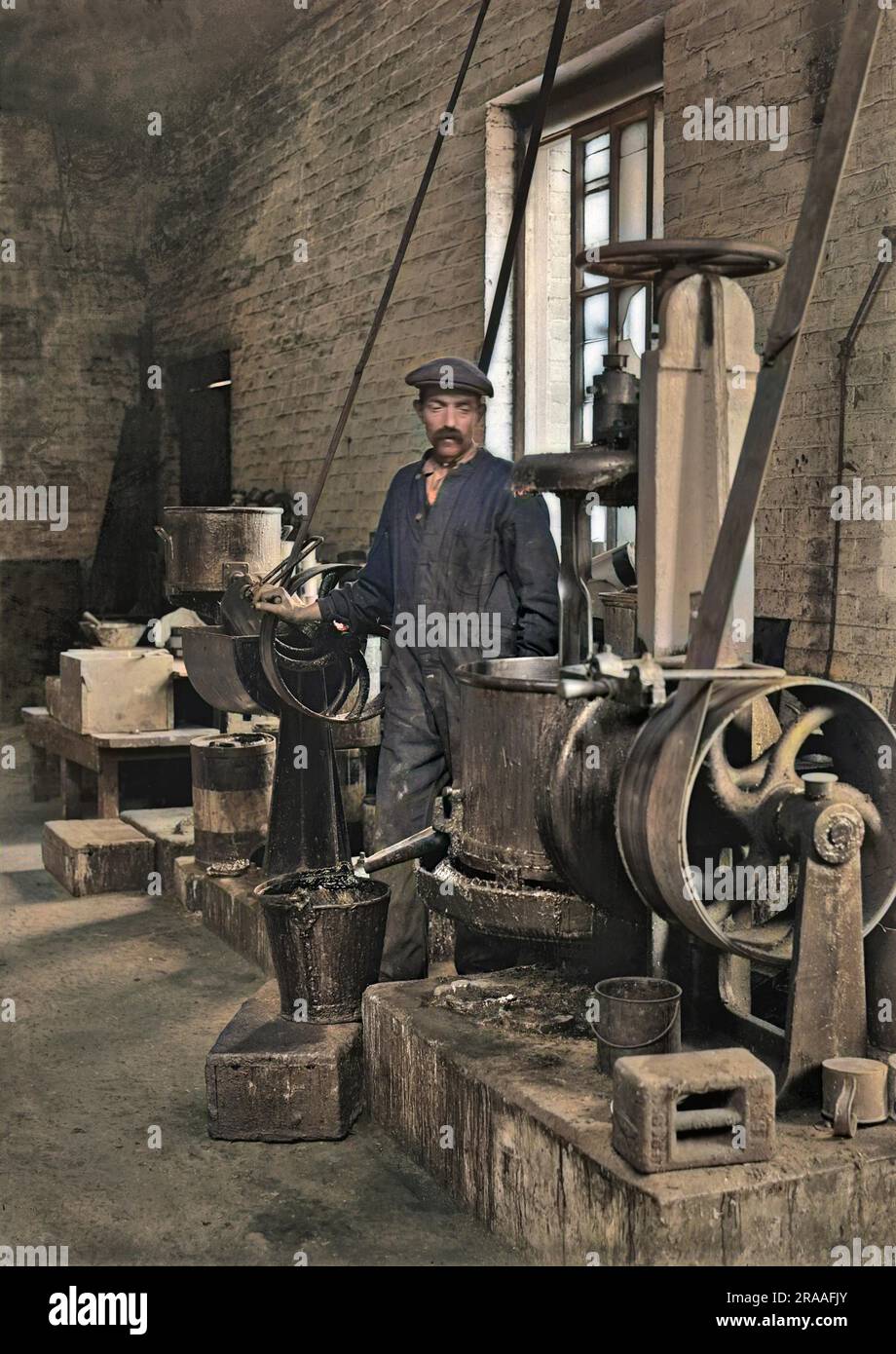 Workman in a factory operating machinery. The factory produced lead shrapnel for the use in high explosive artillery shells during WW1.     Date: circa 1915 Stock Photo