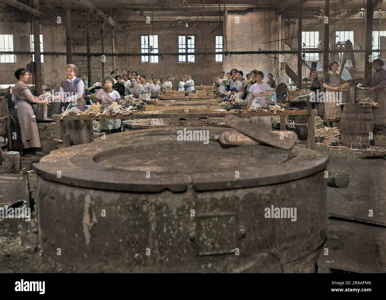 A group of female manual workers in a factory, standing close to vats containing molten lead, using in the manufacturing of shrapnel for WW1 artillery shells.     Date: circa 1915 Stock Photo