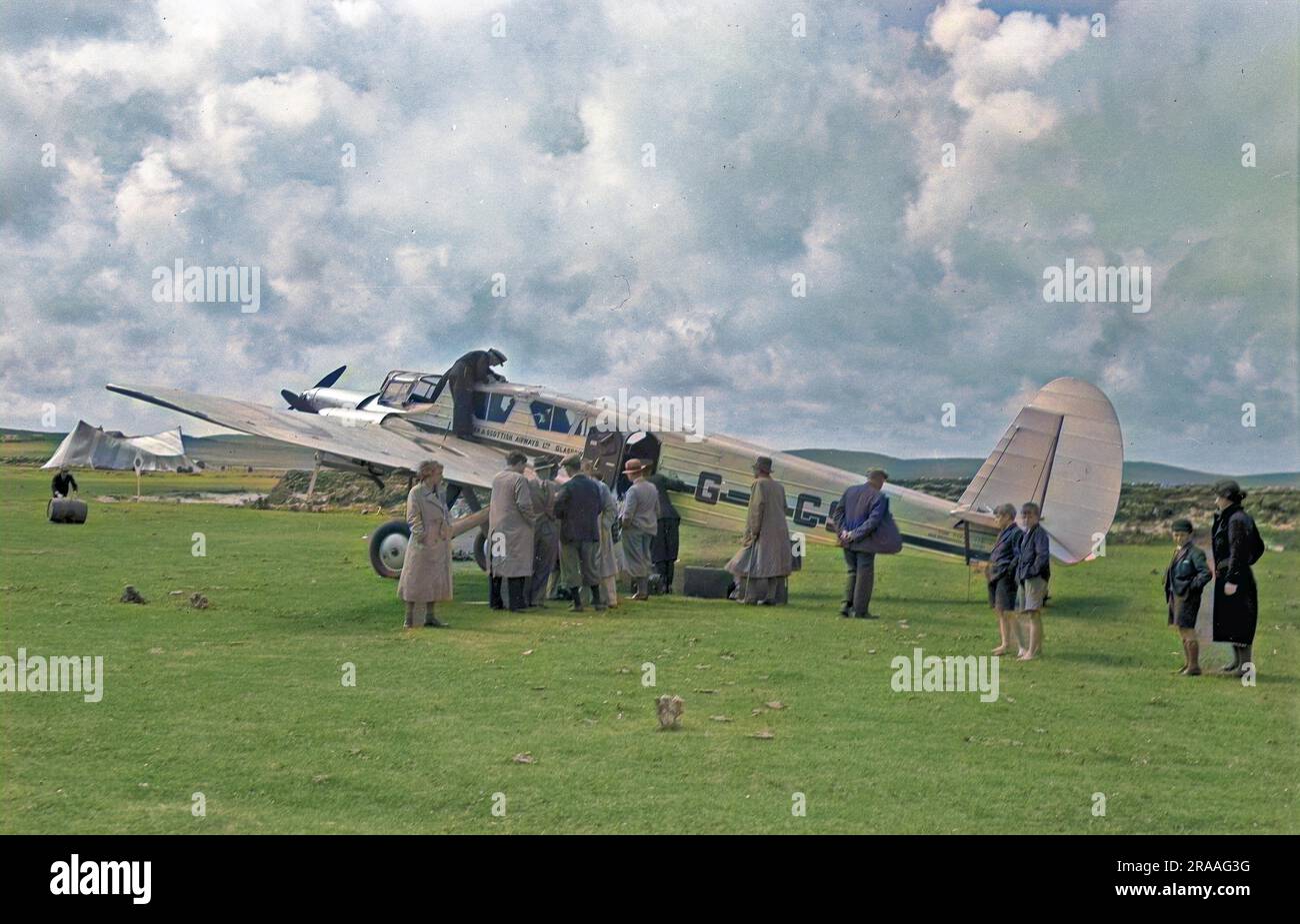 People on an airfield in Scotland with a light aircraft belonging to Northern & Scottish Airways Ltd of Glasgow. The G-ACSM was a Spartan Cruiser with three engines.     Date: 1930s Stock Photo