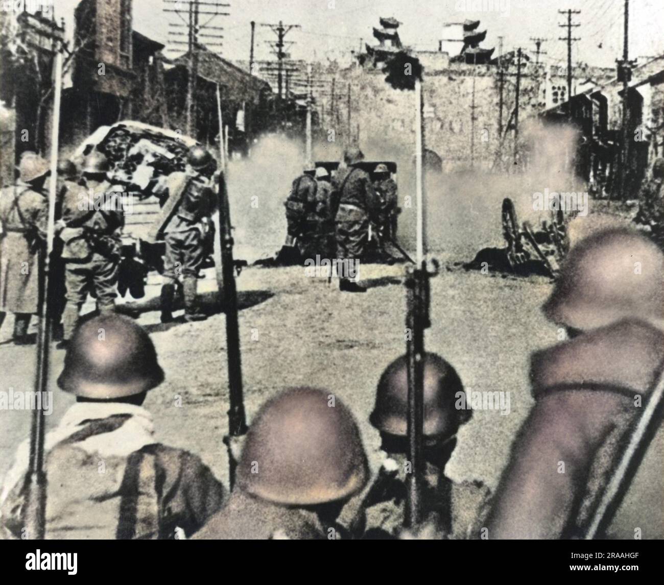 Japanese artillery shell Nanking (Nanjing) from a street facing the South Gate, with infantry waiting to move in to the city.     Date: 1937 Stock Photo