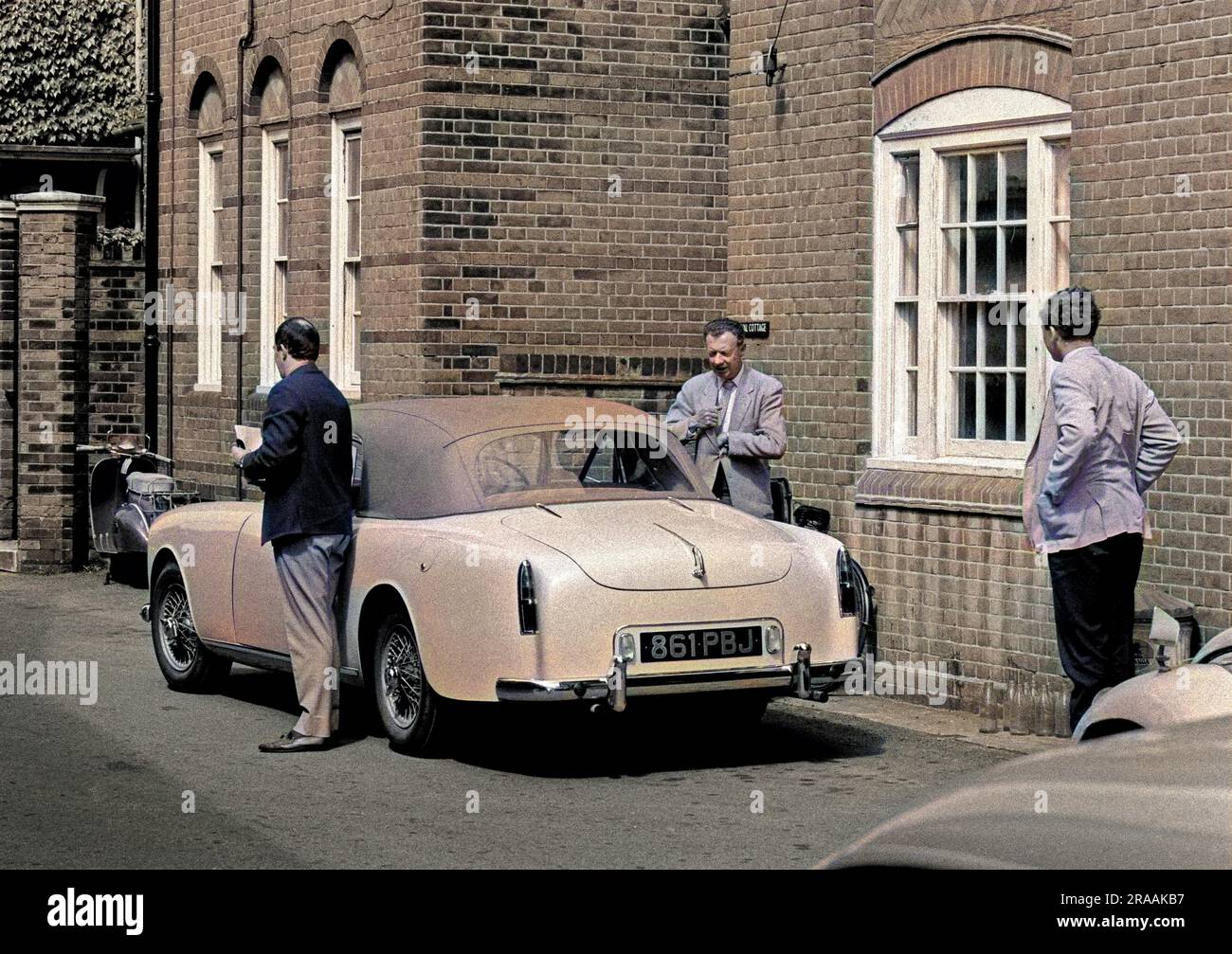Colin Graham (left) and Benjamin Britten leaving his Graber bodied Alvis convertible. The man on the right is unidentified.  This was during rehearsals for the Beggar's Opera a few yards north of the Jubilee Hall, outside what was then Festival Cottage in Crabbe Street (renamed in 1970s-80s Huw House after the welsh-born dachshund who lived in it with Jennifer Andrewes)     Date: 1962 Stock Photo