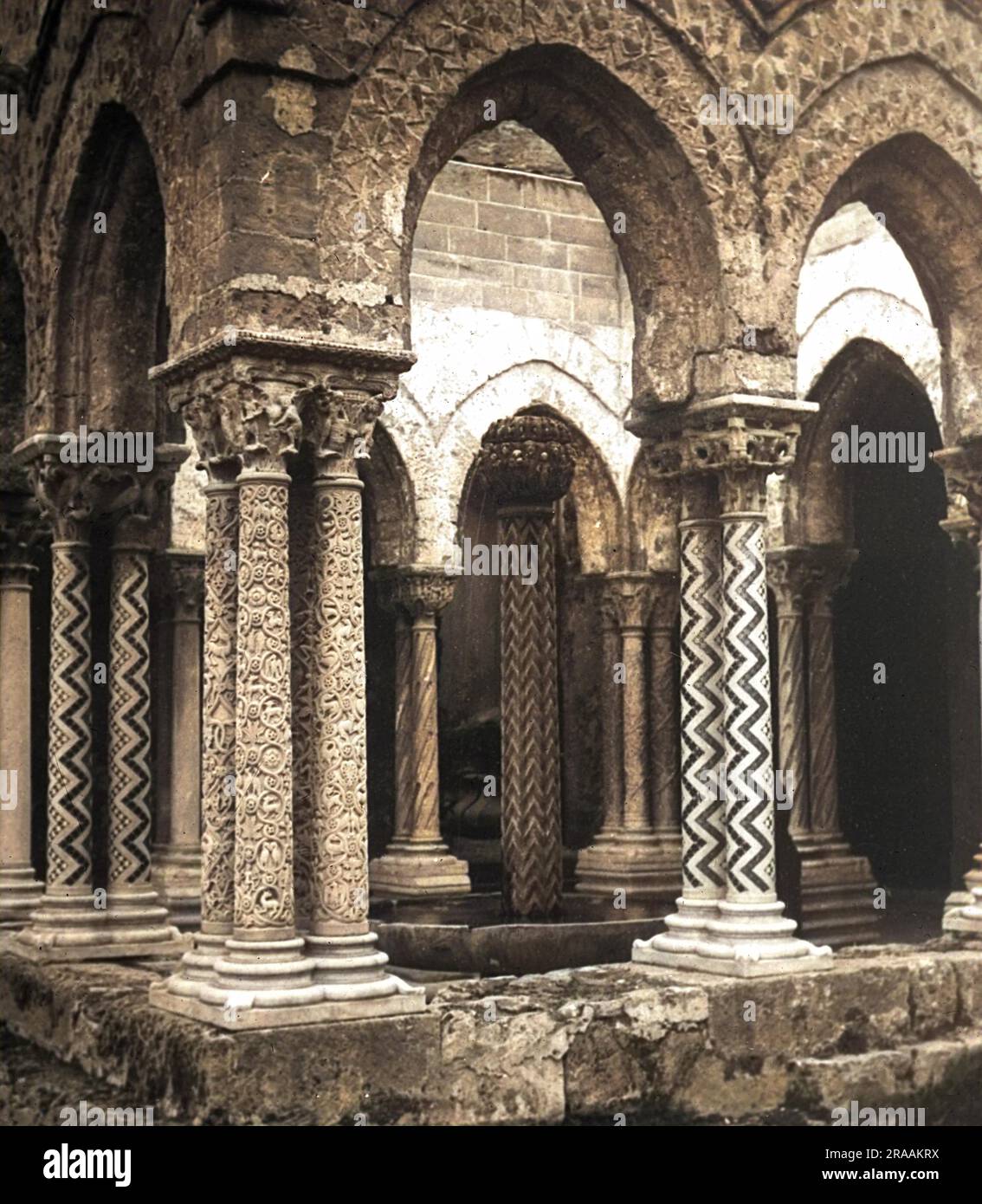 A fine example of cloister architecture with Gothic arches and thin patterned columns. The ante-chamber off the main cloister demarkates an area surrounding a fountain. The Cathedral of Monreale is one of the greatest extant examples of Norman architecture in the world. It was begun in 1174 by William II, and in 1182 the church, dedicated to the Assumption of the Virgin Mary, was, by a bull of Pope Lucius III, elevated to the rank of a metropolitan cathedral. The church is a national monument of Italy and one of the most important attractions of Sicily.     Date: circa 1904 Stock Photo