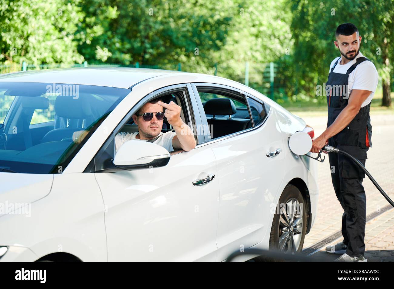 Rude driver showing middle finger to other car on gas station. Angry