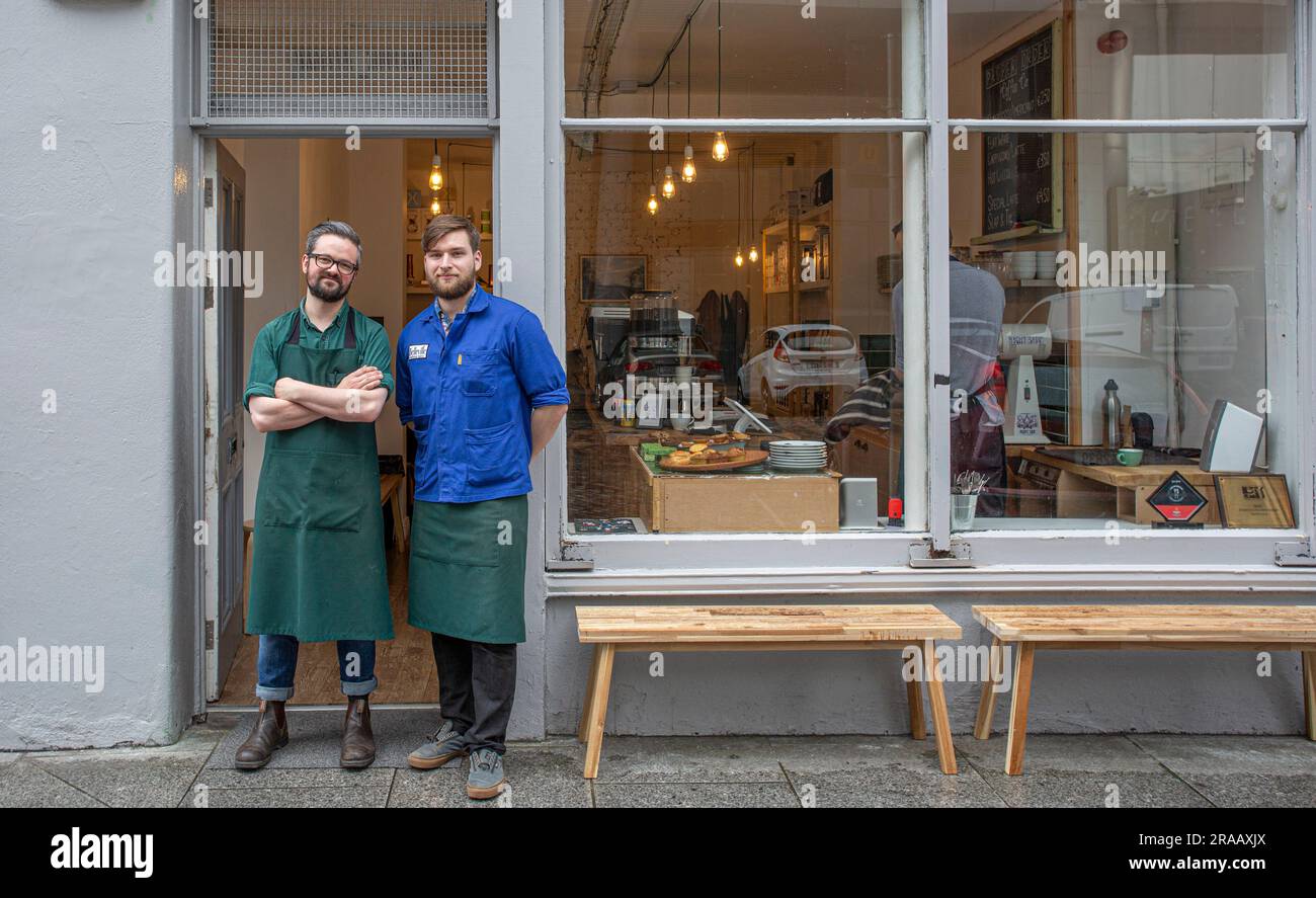 Two young male owner standing at the entrance of their coffee shop Stock Photo