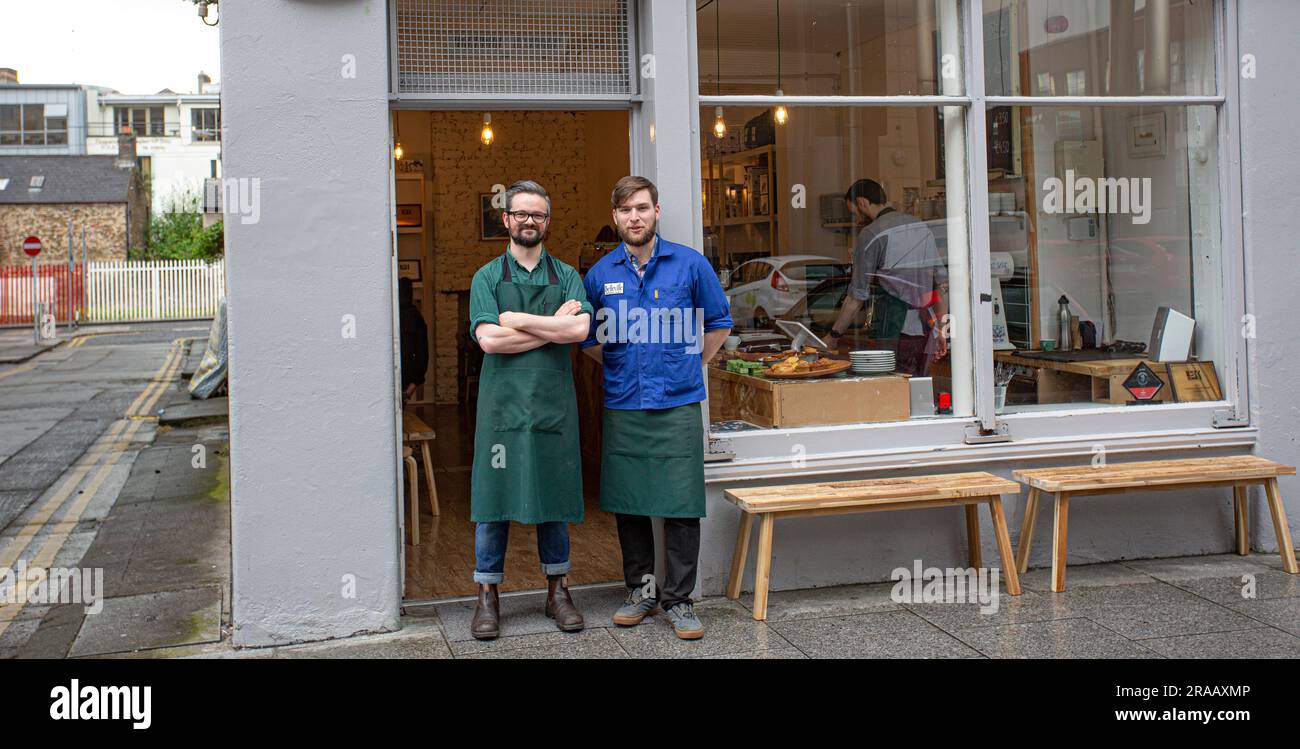 Two happy young cafe owner in front of coffee shop smiling. Stock Photo