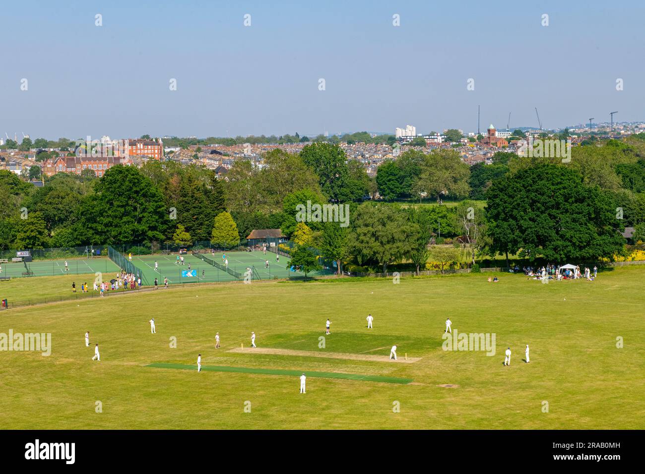 A panoramic view over a cricket match on Wandsworth Common in London with the City of London and the Docklands in the distance Stock Photo