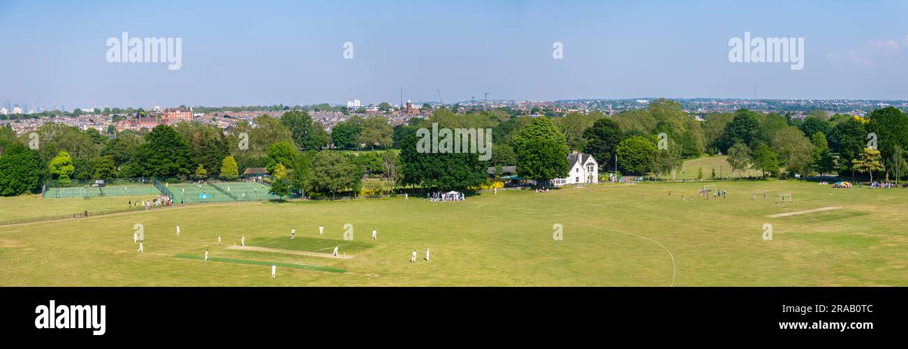 A panoramic view over a cricket match on Wandsworth Common in London with the City of London and the Docklands in the distance Stock Photo