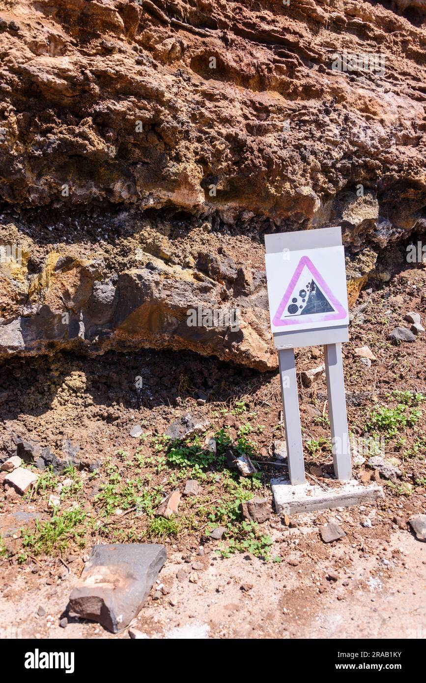 Sign warning people of the danger of rocks falling from an unstable cliff. Stock Photo