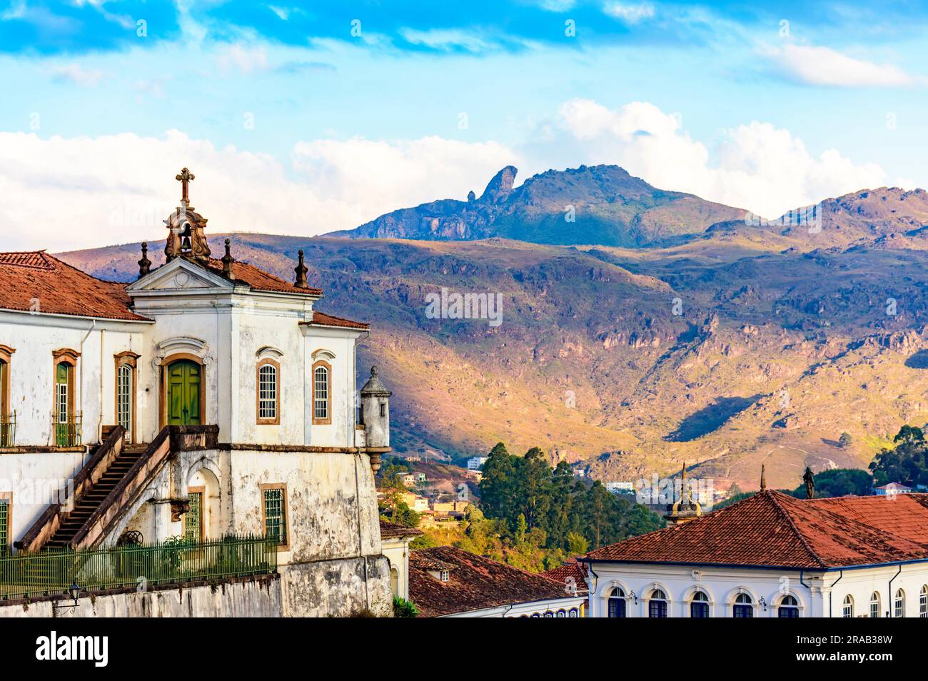 Baroque church and mountains in the city of Ouro Preto in Minas Gerais with the mountains and peak of Itacolomi in the background during sunset Stock Photo
