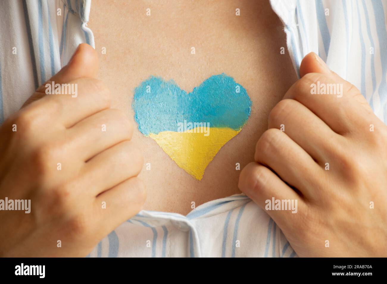 The flag of Ukraine in the form of a heart is painted on the girl s chest, and her hands hold on to her shirt, peace and hope, volunteer Stock Photo