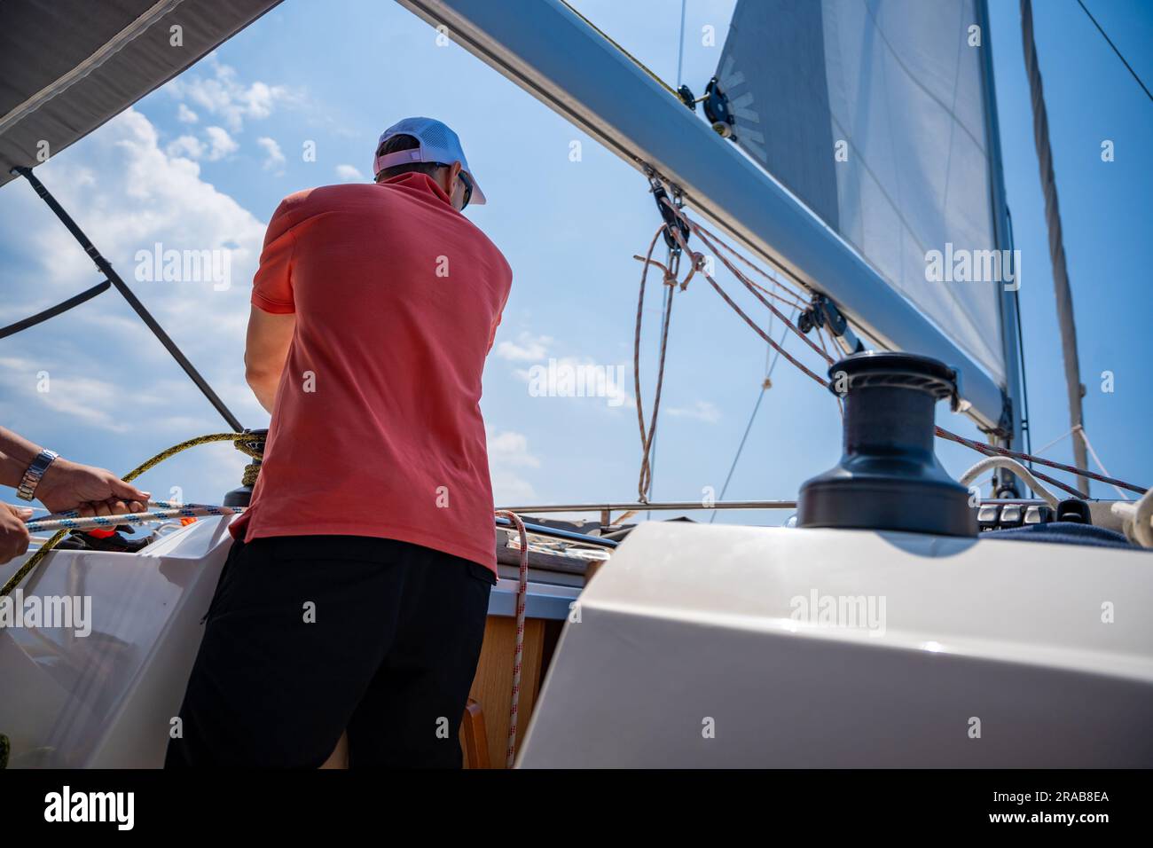 Mans pulling winch rope on sailing boat Stock Photo