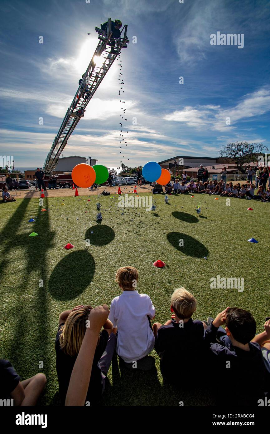 Numbered golf balls are dropped from the ladder of a fire truck onto