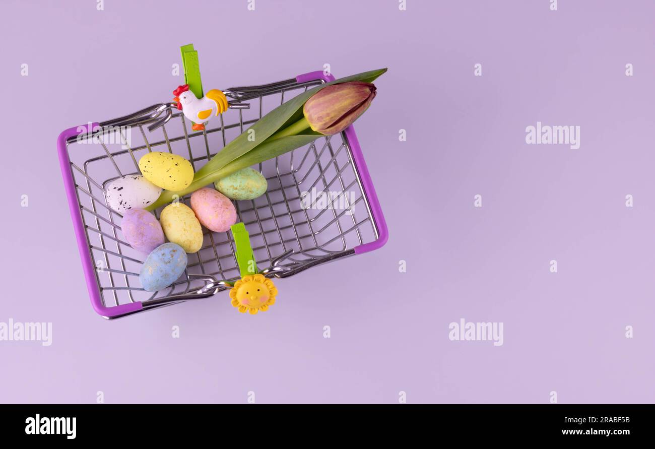 In the basket of the buyer are colorful eggs, a tulip and bright green clothespins Stock Photo