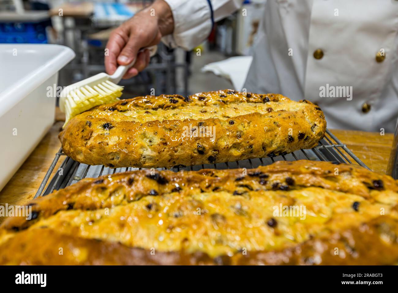 Production of an original Dresden Christstollen in Dresden, Germany. Dresdner Christstollen gets a natural preservation by applying liquid butter with a brush Stock Photo