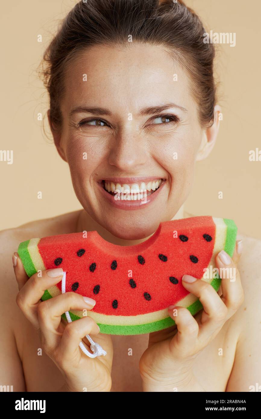 happy 40 years old woman with watermelon shower sponge on beige