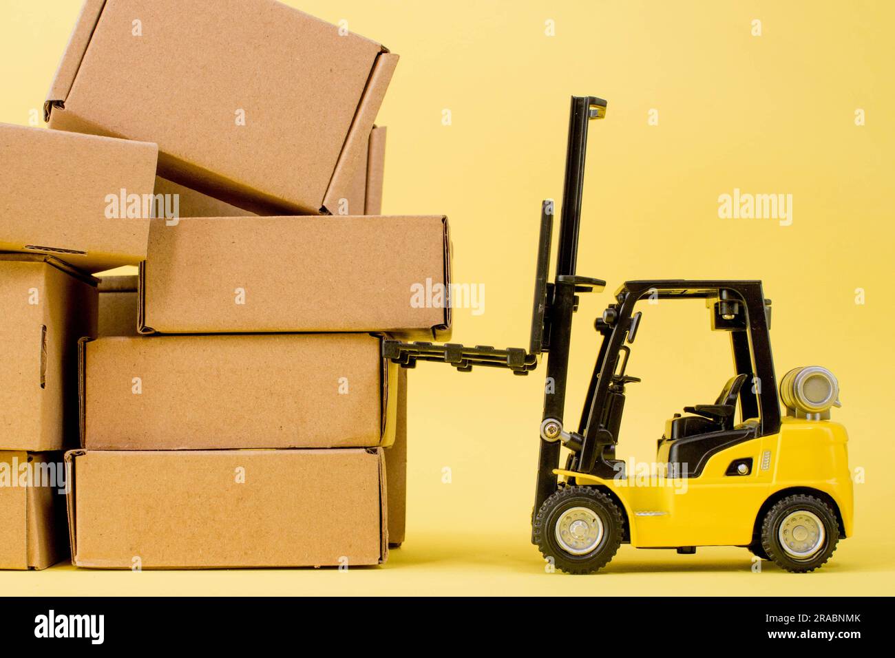 Forklift truck raises cardboard boxes on a yellow background. Cargo ...