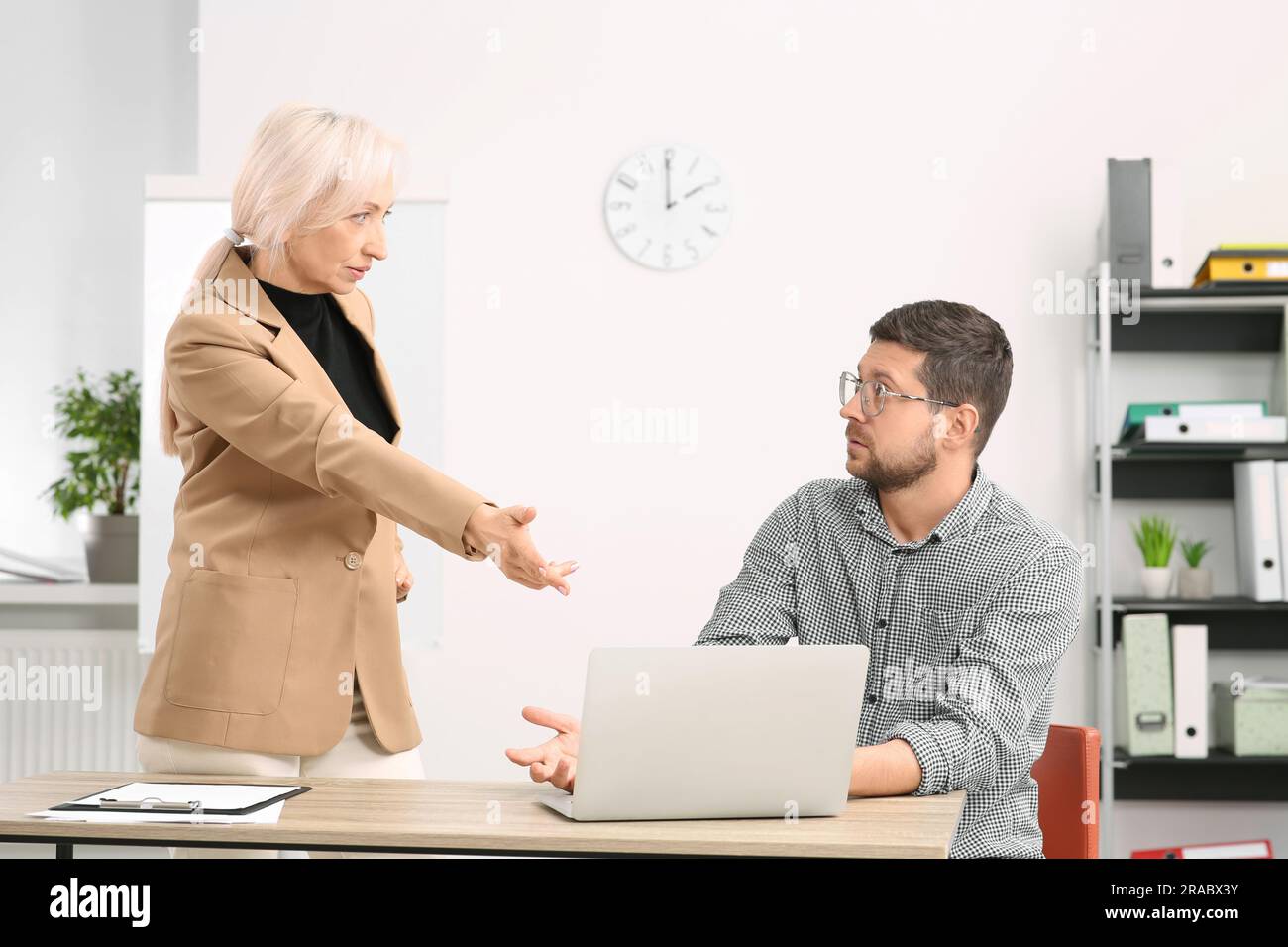 Emotional boss and confused employee discussing work issues in office