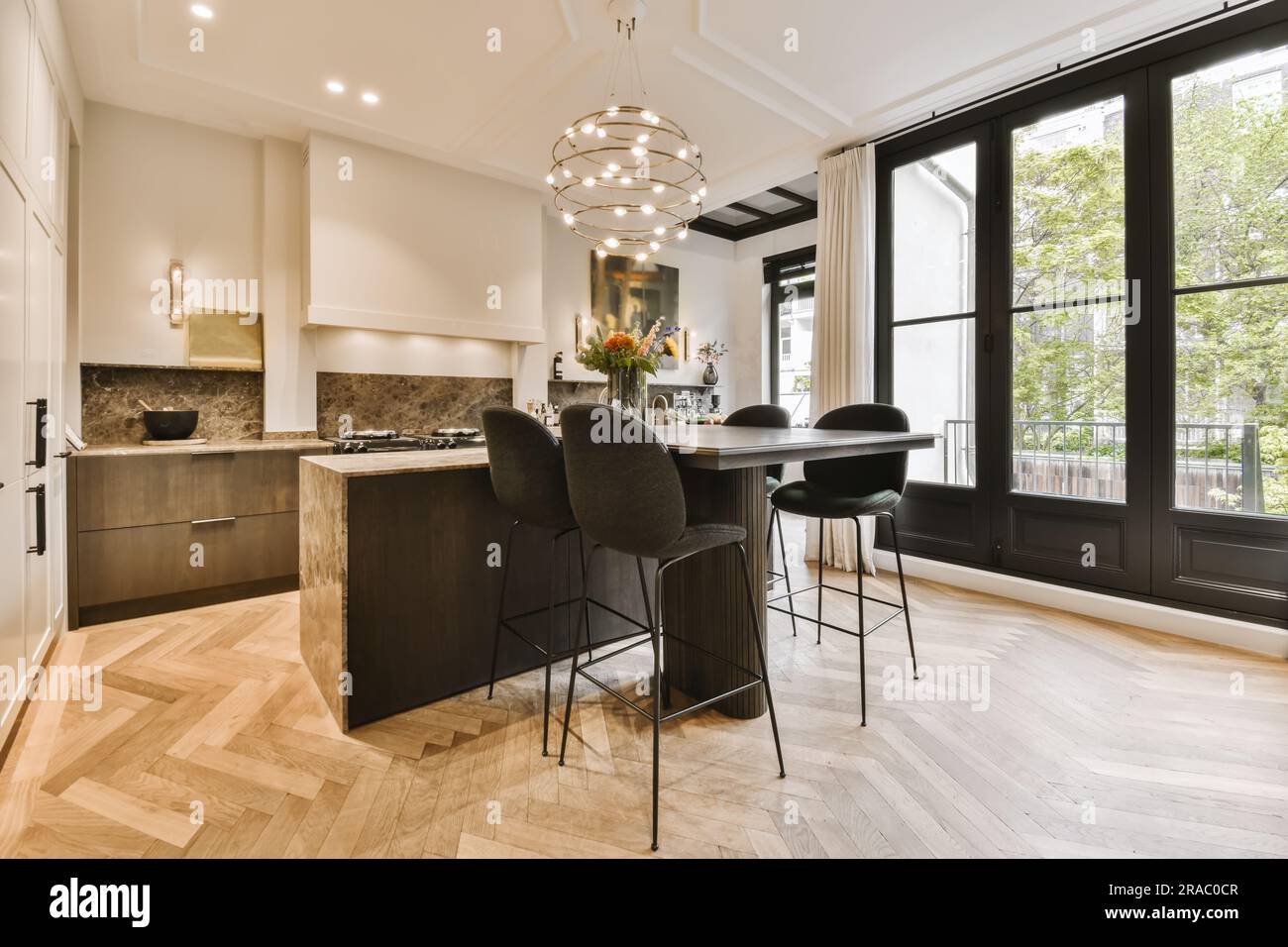 a kitchen and dining area in a house with wood flooring, white walls and  black trim around the windows Stock Photo - Alamy, image size:1300x956