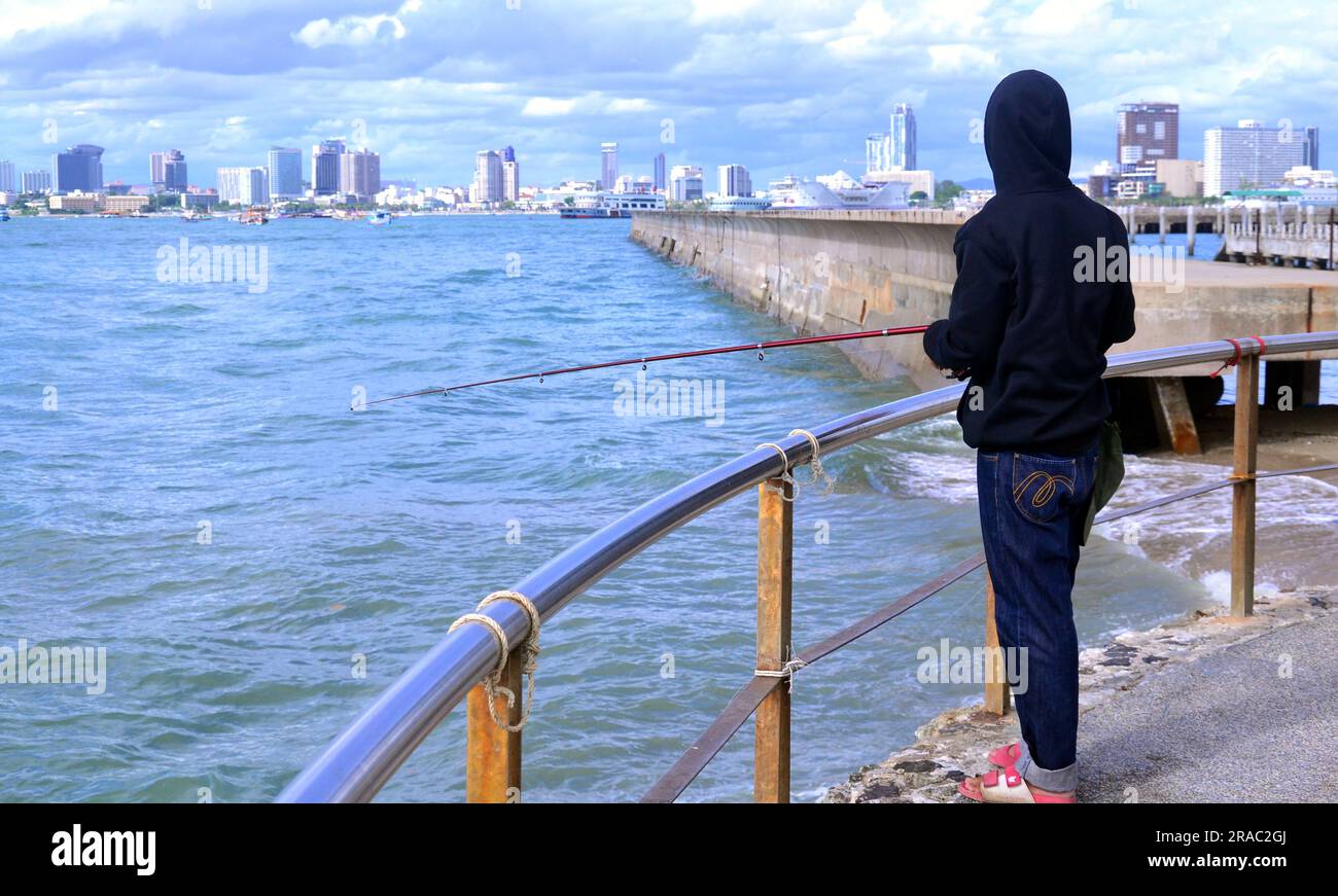 A young fisherman fishing in the sea at Cape Bali Hai, Pattaya
