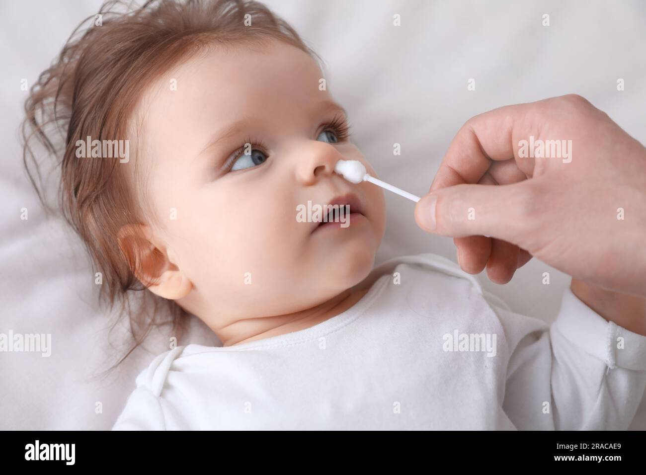 https://c8.alamy.com/comp/2RACAE9/father-cleaning-nose-of-his-baby-with-cotton-bud-on-bed-closeup-2RACAE9.jpg