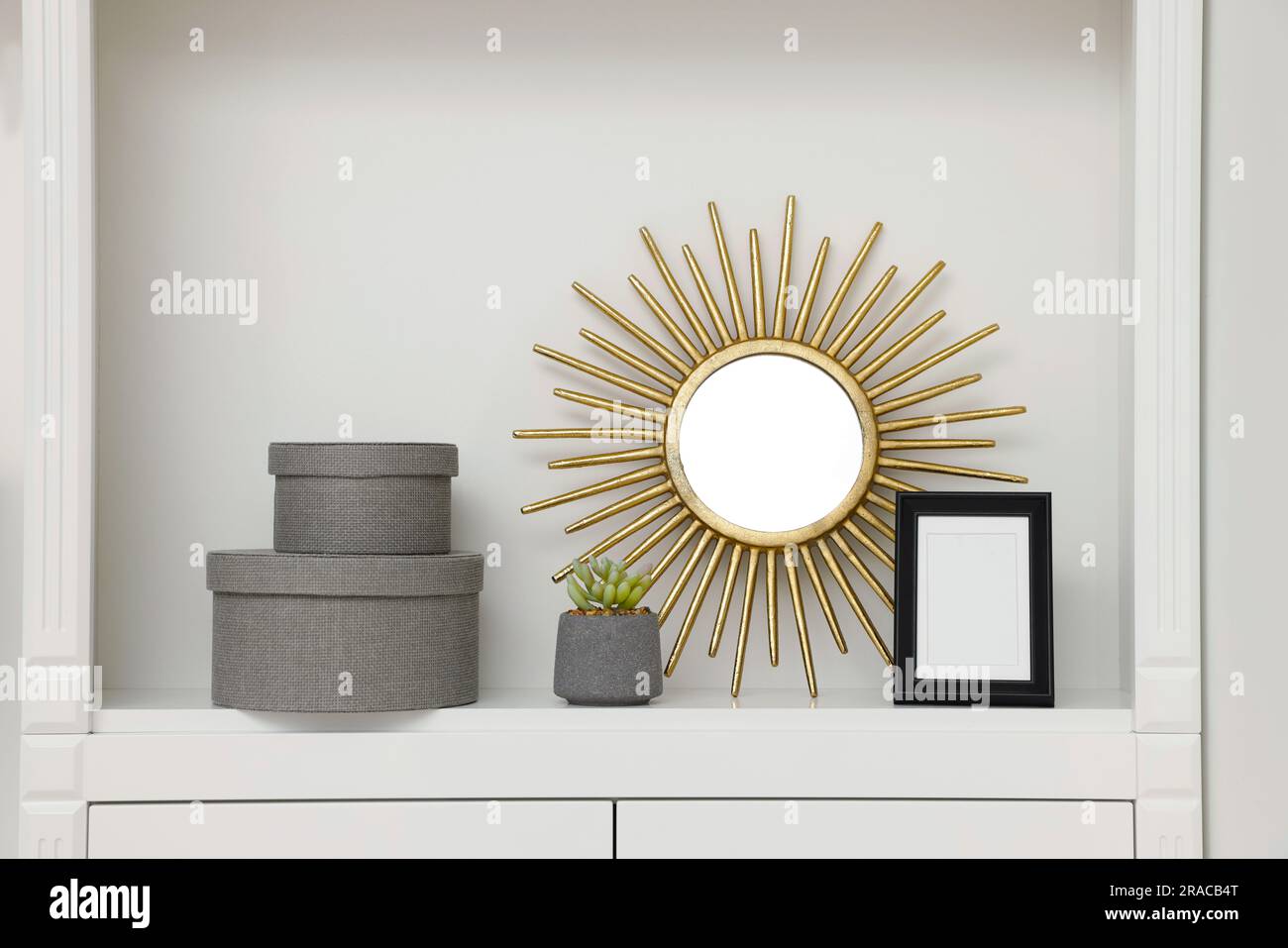 Grey decorative boxes, houseplant, mirror and frame on shelving unit