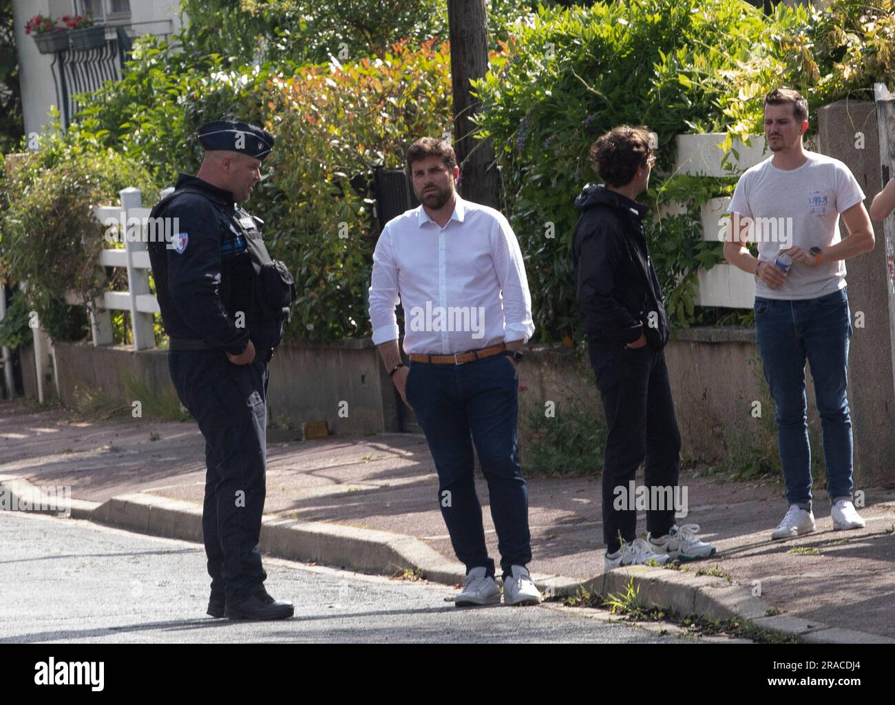 Mayor Vincent Jeanbrun (2L) stands under police protection outside his house on July 2, 2023 in L'Hay-les-Roses, a Paris suburb, France. Attackers tried to set fire to his home of overnight and fired rockets at the official's fleeing wife and children. The incident has caused widespread shock and is being treated as attempted murder. Mayor Vincent Jeanbrun was not at home, but his wife suffered a broken leg and his child was also hurt. France has seen violent protests after police killed a teenager on Tuesday. Photo by Jeremy Paoloni/ABACAPRESS.COM Credit: Abaca Press/Alamy Live News Stock Photo