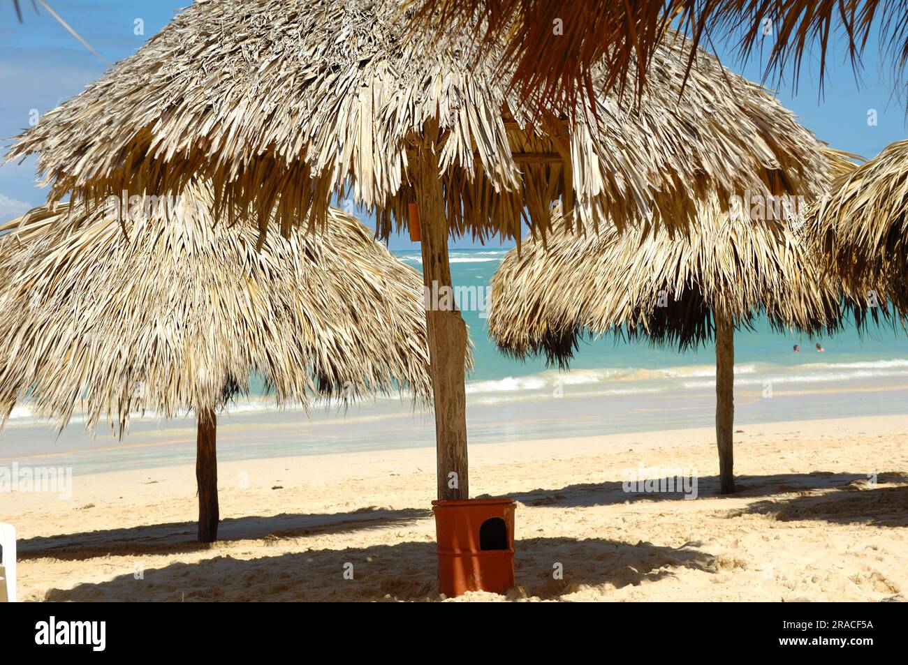 Parasols made out of palm leafs on exotic beach. In the background is