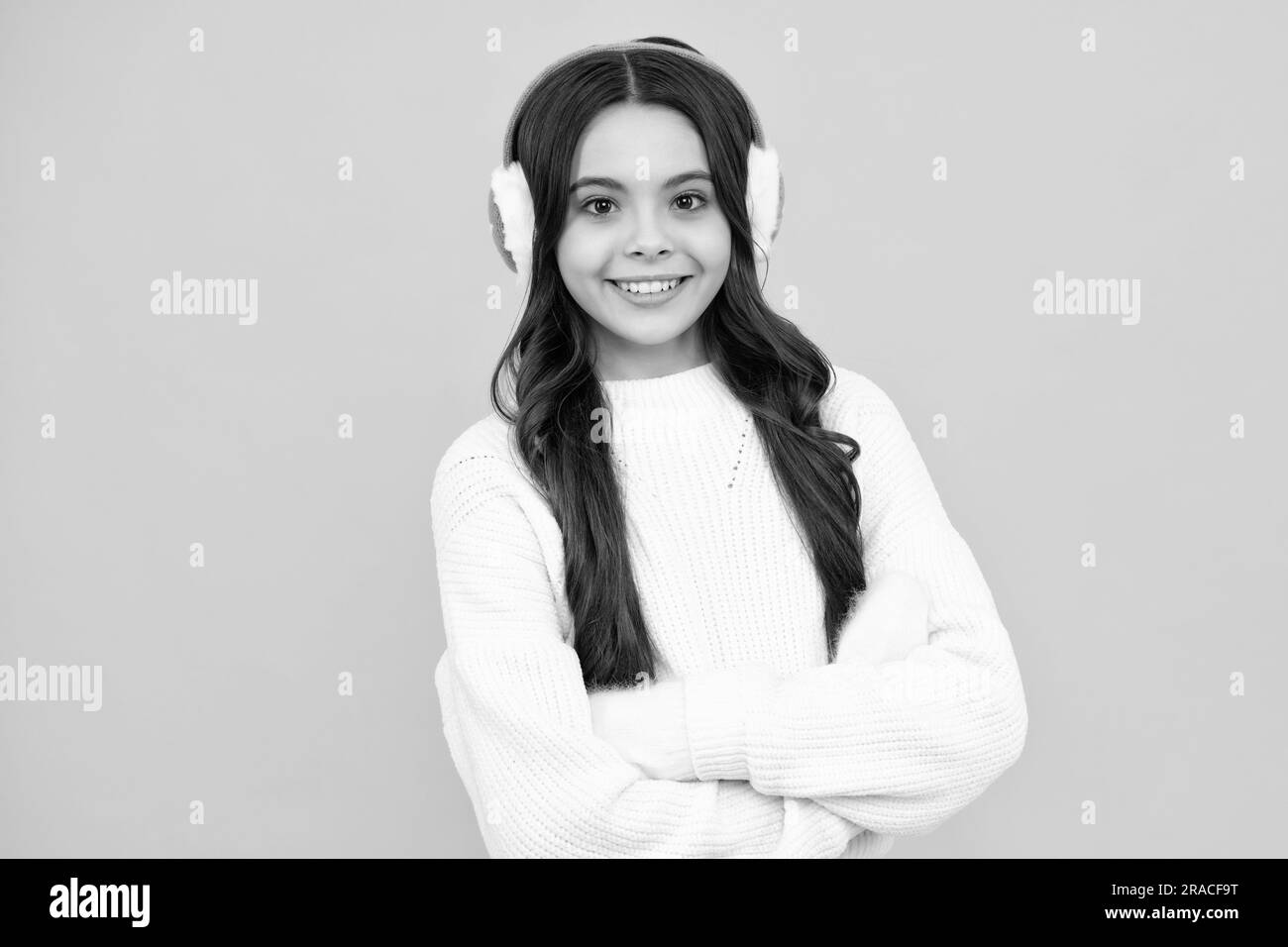 Beautiful teen girl in a winter warm earmuff ear-flaps and a warm sweater.  A child on a yellow isolated background Stock Photo - Alamy