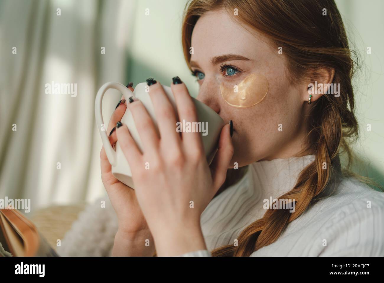 Woman drinking hot beverage and reading book Stock Photo