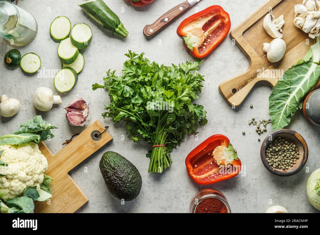 Healthy cooking and eating with fresh herbs and various vegetables ingredients on kitchen desk with knife and cutting board. Top view Stock Photo