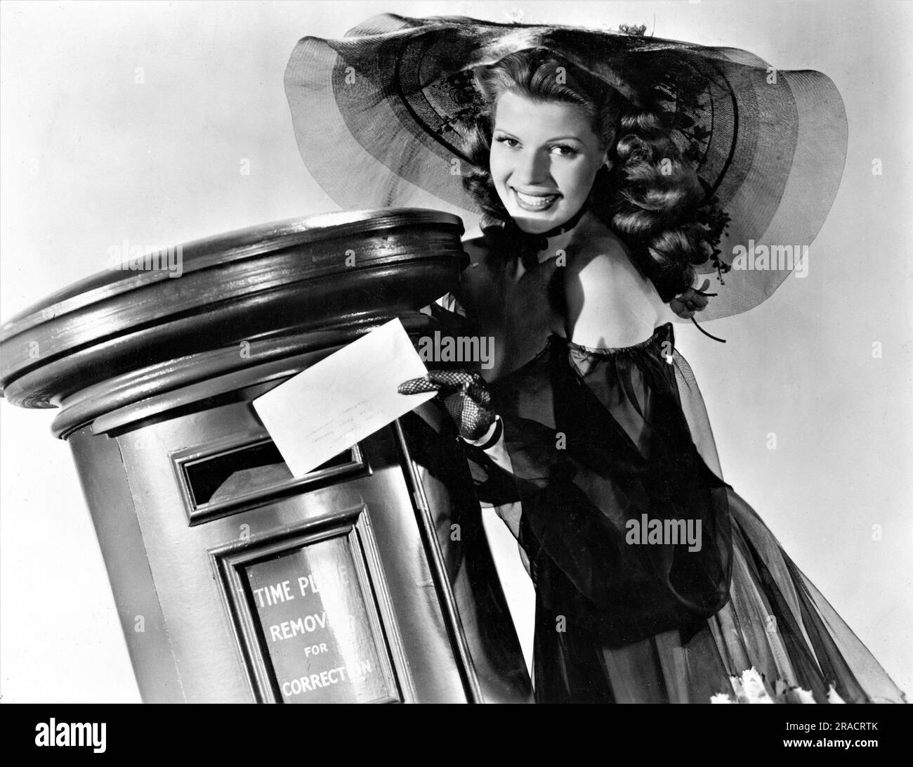 RITA HAYWORTH posts letter in British Post Box in costume for TONIGHT AND EVERY NIGHT 1945 director / producer VICTOR SAVILLE play Lesley Storm gowns and costumes Jean Louis and Marcel Vertes Columbia Pictures Stock Photo