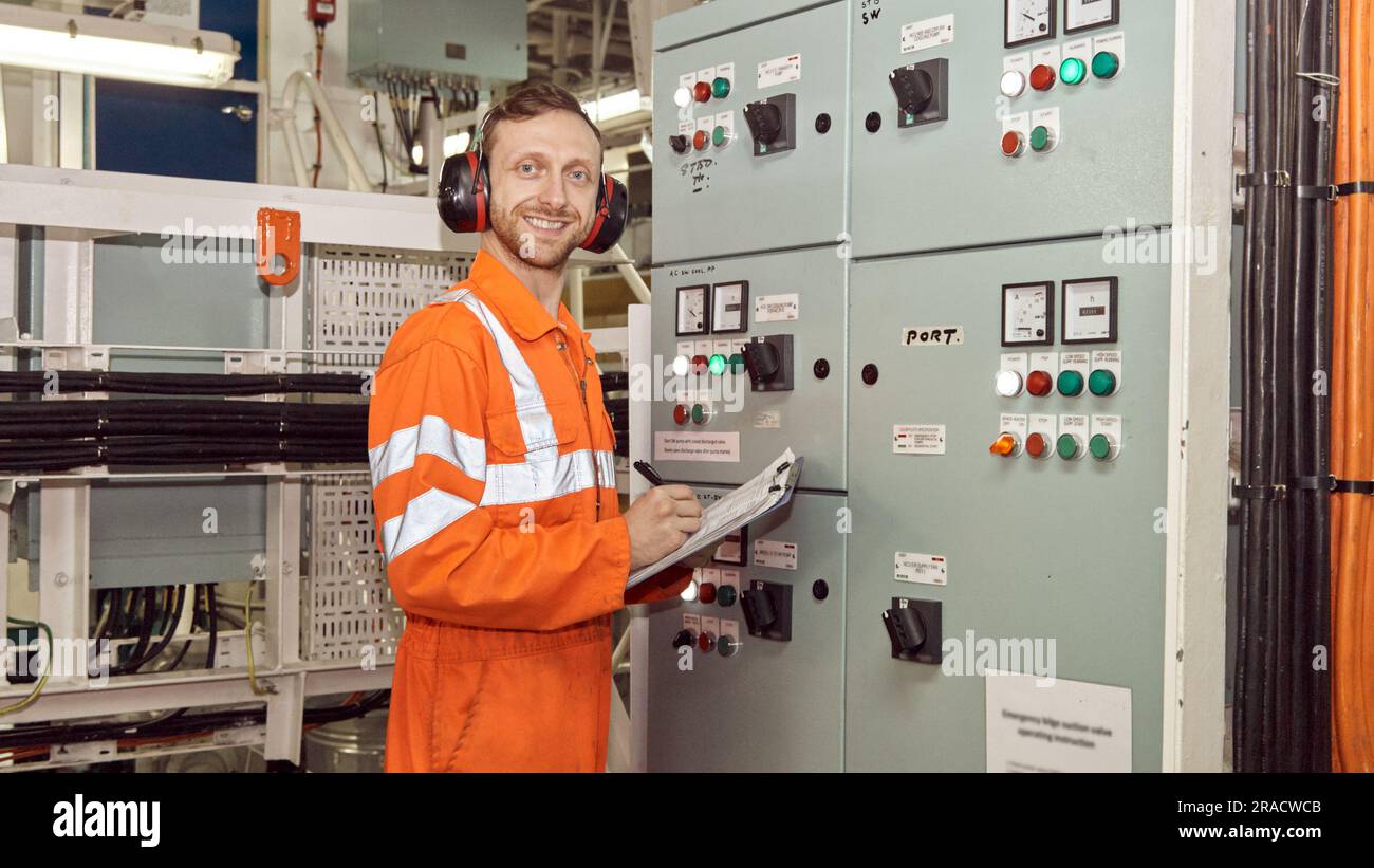 Young marine engineer making notes in engine room log book. Offshore