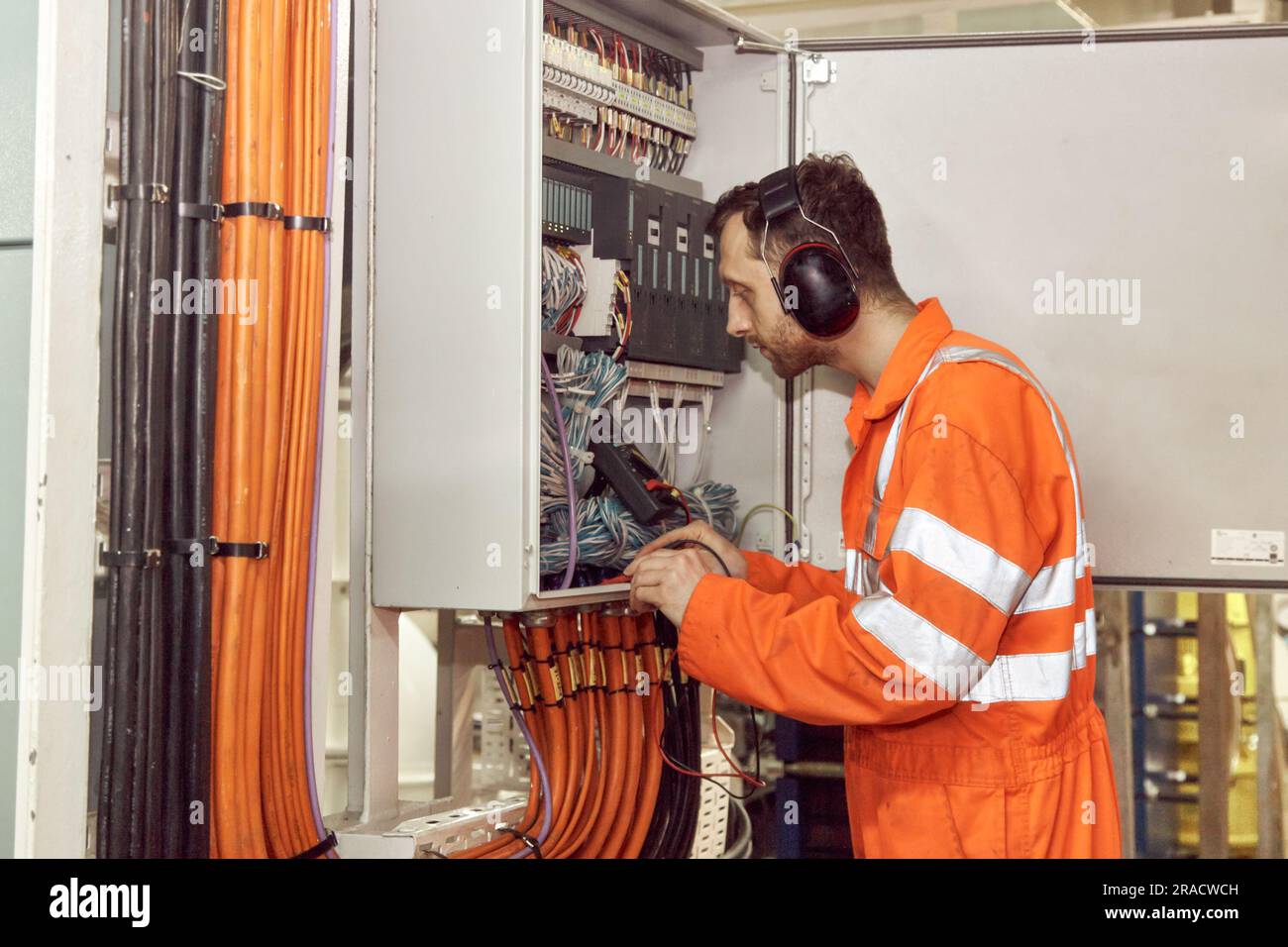 Marine electrical engineer officer checking electrical switchboard with digital multi meter