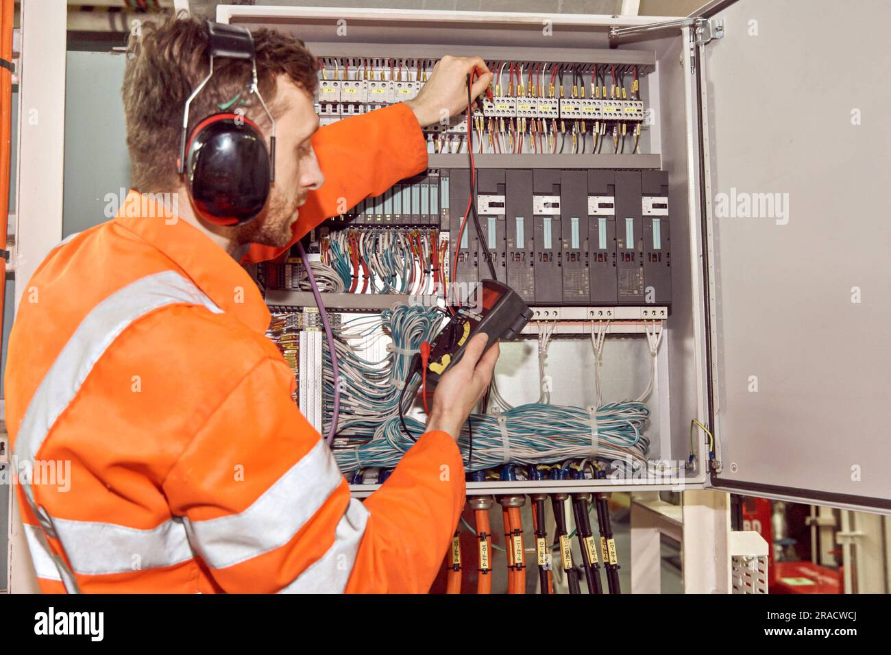 Offshore oil and gas electrical engineer checking electrical switchboard with multi meter. Stock Photo