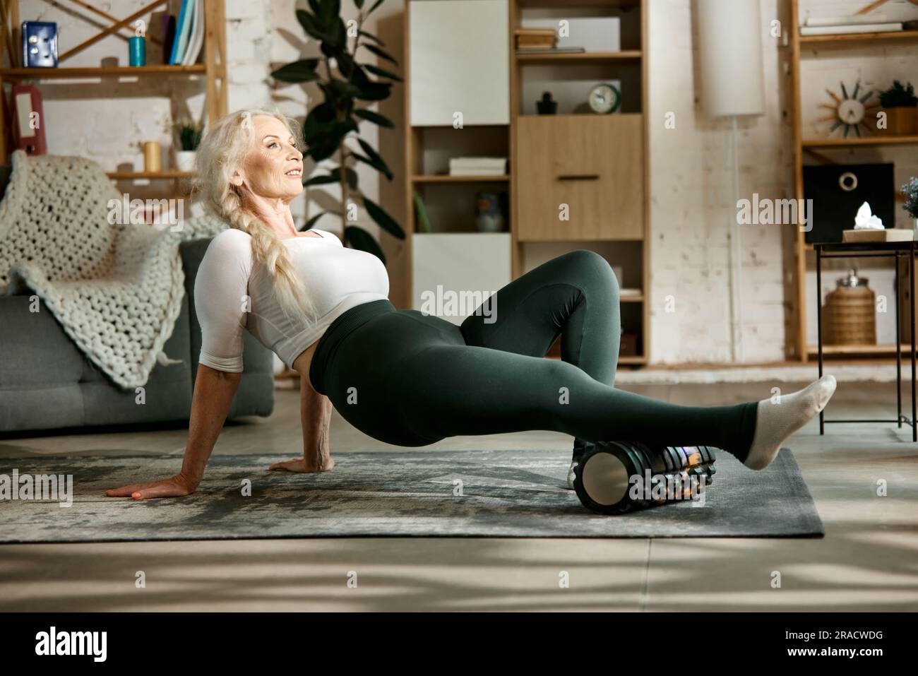 Slim sportive beautiful senior woman training at home keeping body in tone with fitness massage roller Stock Photo Alamy