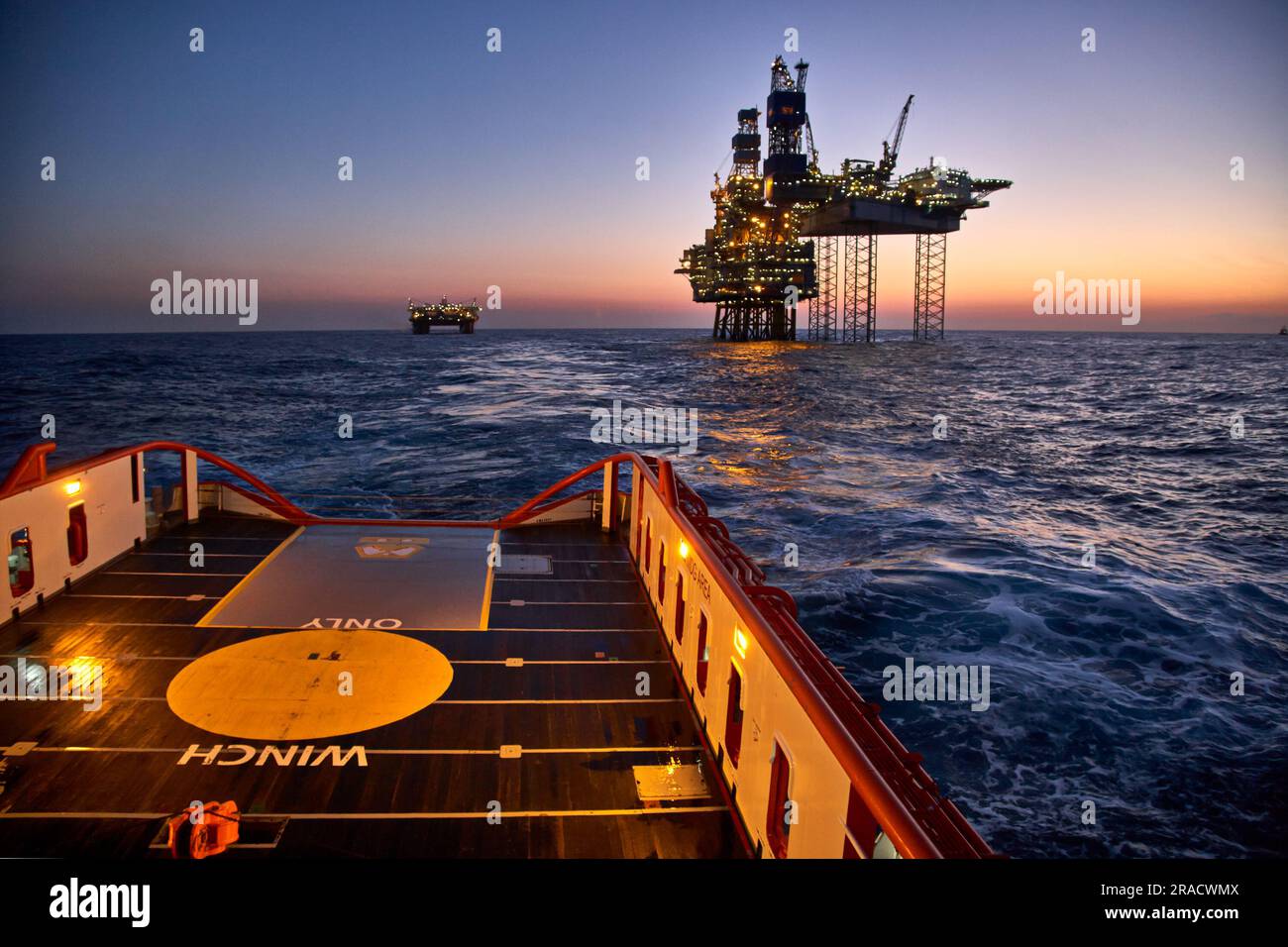 Supply vessel going for cargo operations with jack-up rig. Stock Photo